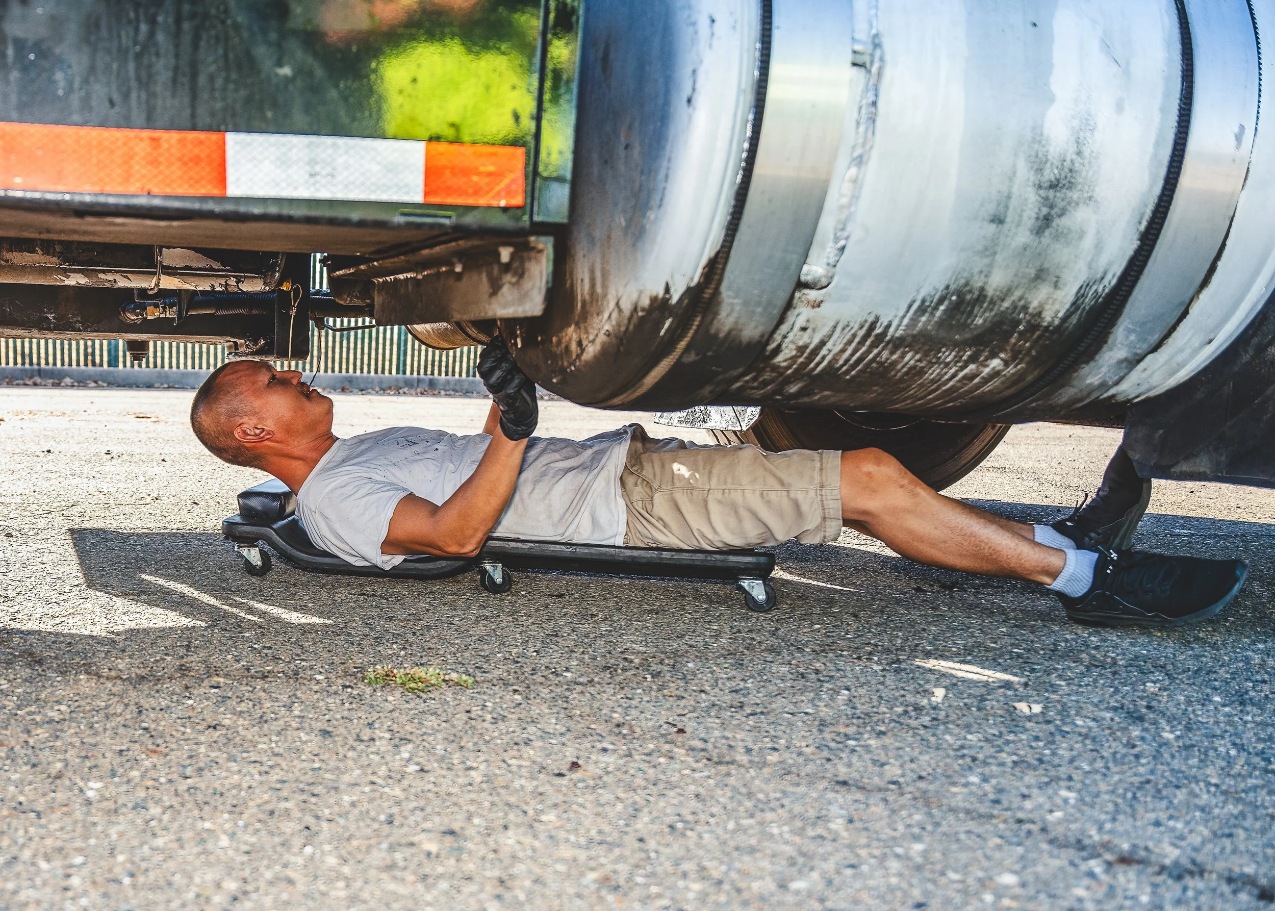 Technician performing repair work underneath a large industrial vehicle