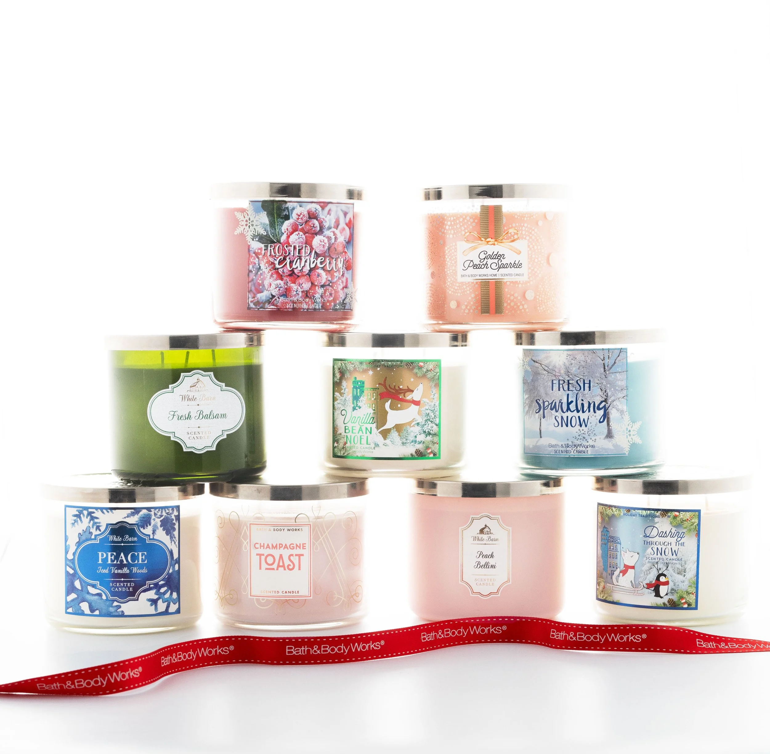 A collection of nine Bath and Body Works scented candles with holiday-themed labels arranged in three rows, with a red Bath & Body Works ribbon in front.