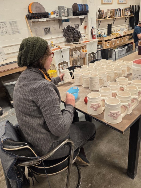 A potter, Sarah, filling in custom made medallions with custom made red glaze. Made at Old School Farm Pottery, a nonprofit Nashville Pottery.
