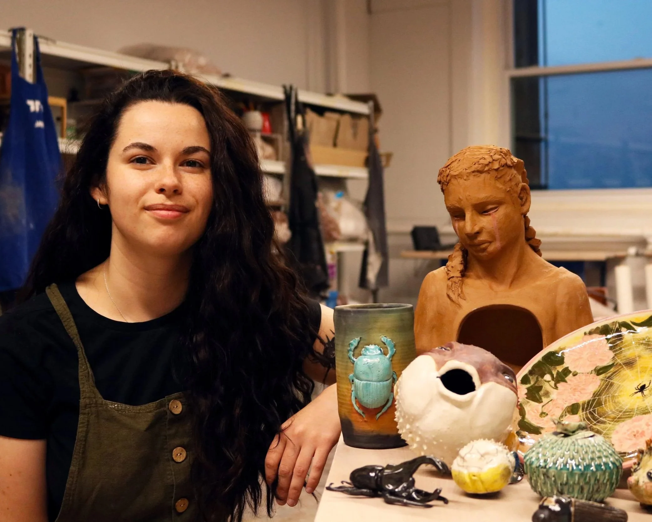 Andi sitting next to a collection of her pieces.
