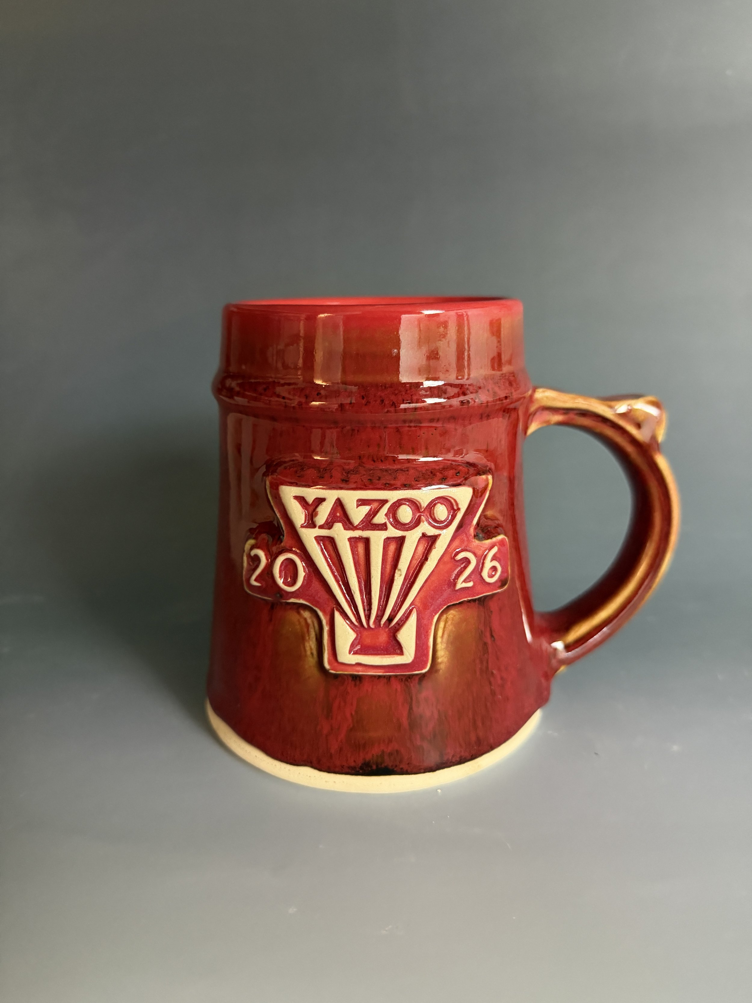 A completed Yazoo 2026 Mug Club Mug. Glazed with a custom red and tenmoku glaze. Made at Old School Farm Pottery, a nonprofit Nashville Pottery.