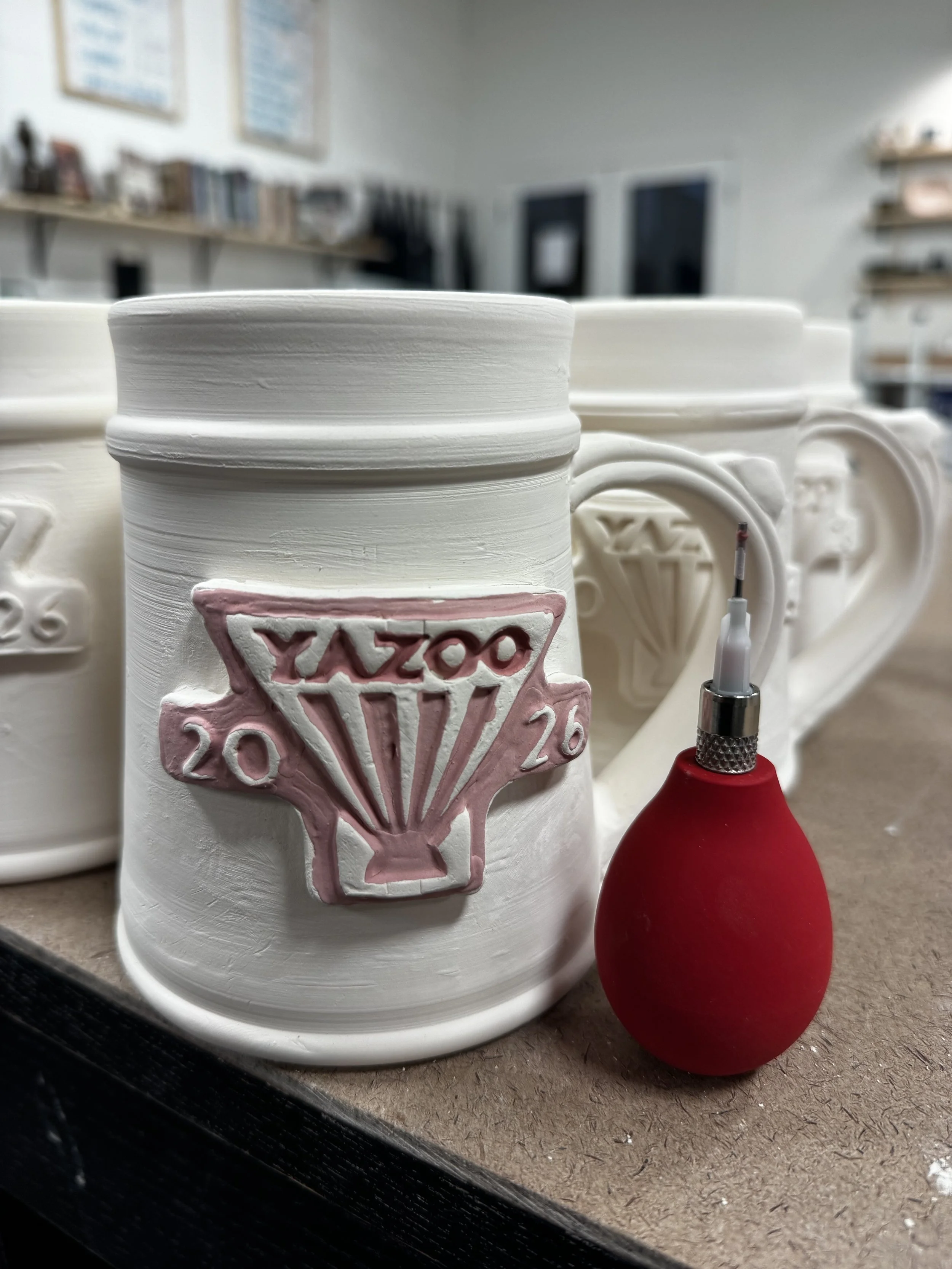 A custom made medallions filled with custom made red glaze, pictured with the bulb used to hand-fill the design. Made at Old School Farm Pottery, a nonprofit Nashville Pottery.