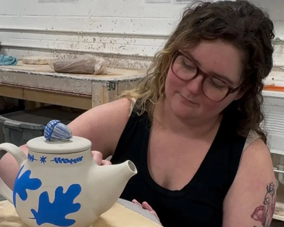 Sarah painting a porcelain teapot in a delftware style. At Old School Farm Pottery, a nonprofit Nashville Pottery