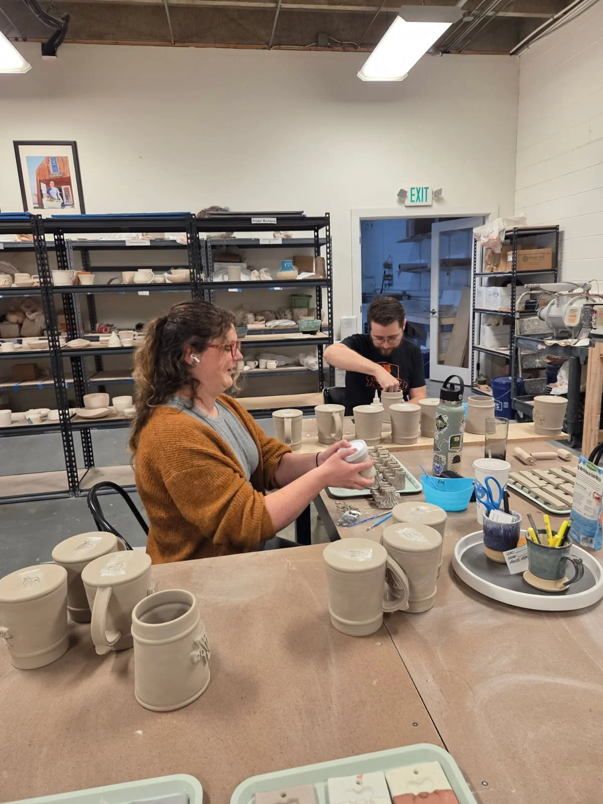 Two potters attaching handles and custom medallions to thrown mug forms. Made at Old School Farm Pottery, a nonprofit Nashville Pottery.