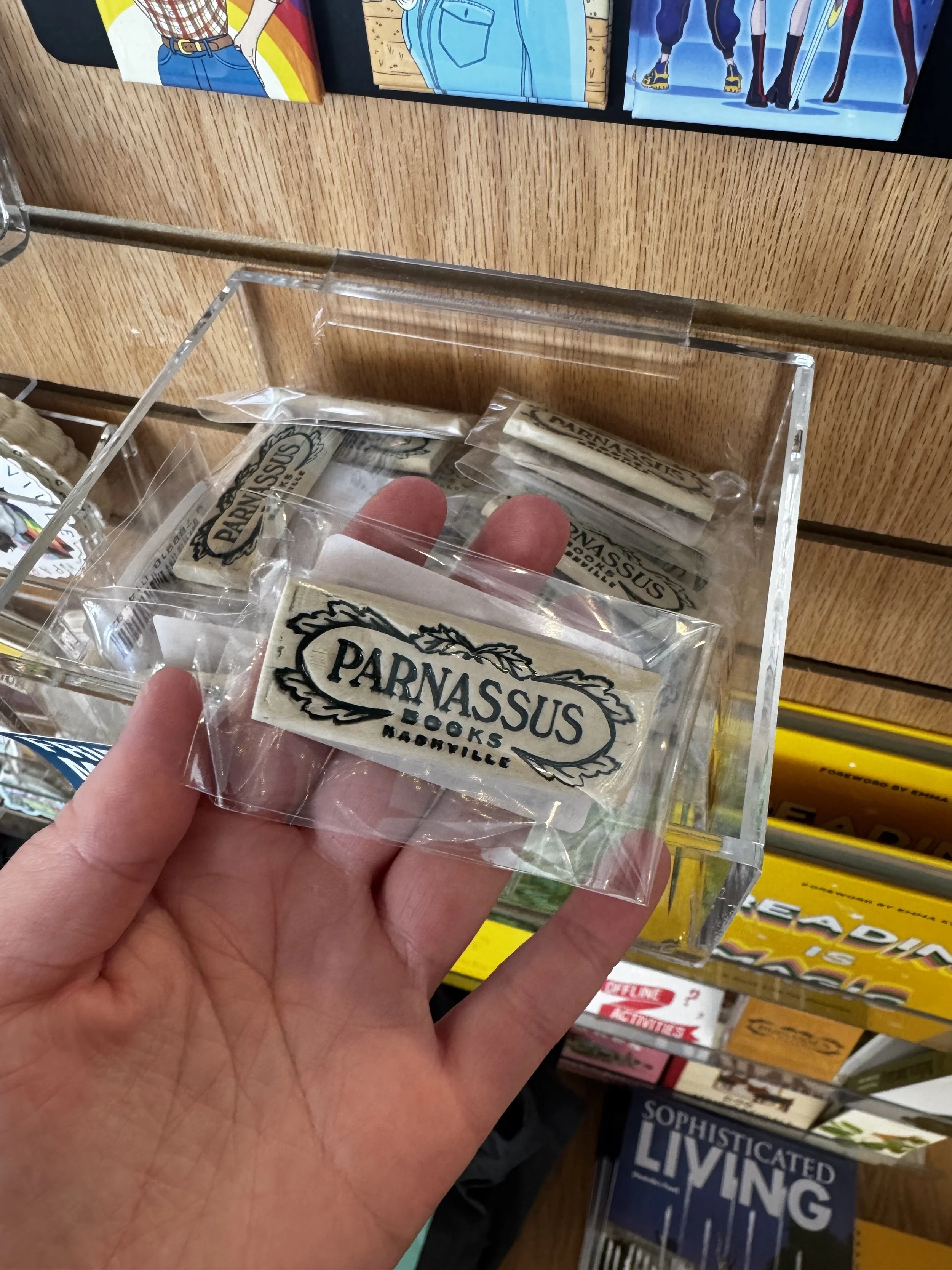 A packaged ceramic magnet with the Parnassus Books logo in dark teal glaze. Made at Old School Farm Pottery, a nonprofit Nashville pottery