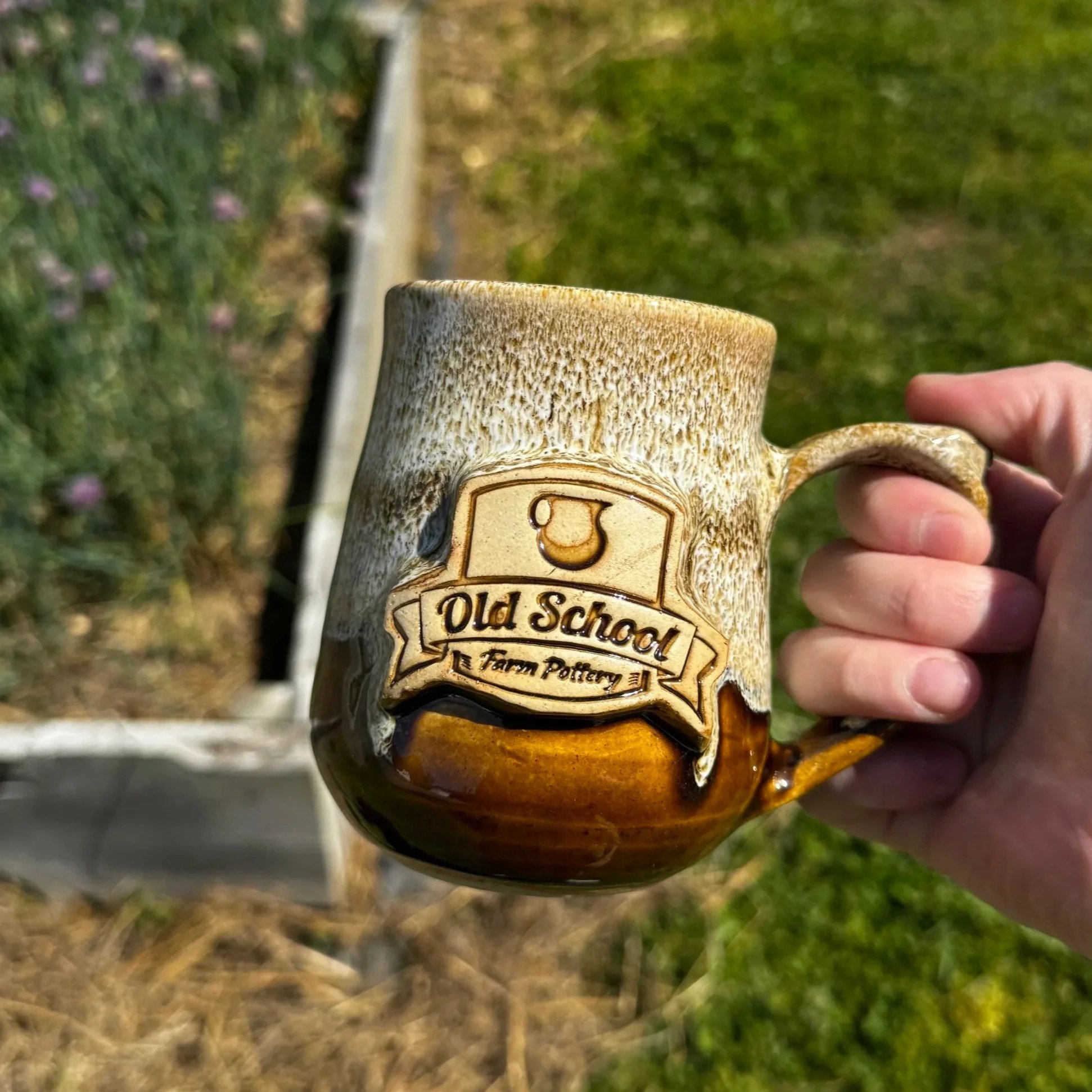 A brown and white mug with a custom logo. Made at Old School Farm Pottery, a nonprofit Nashville pottery