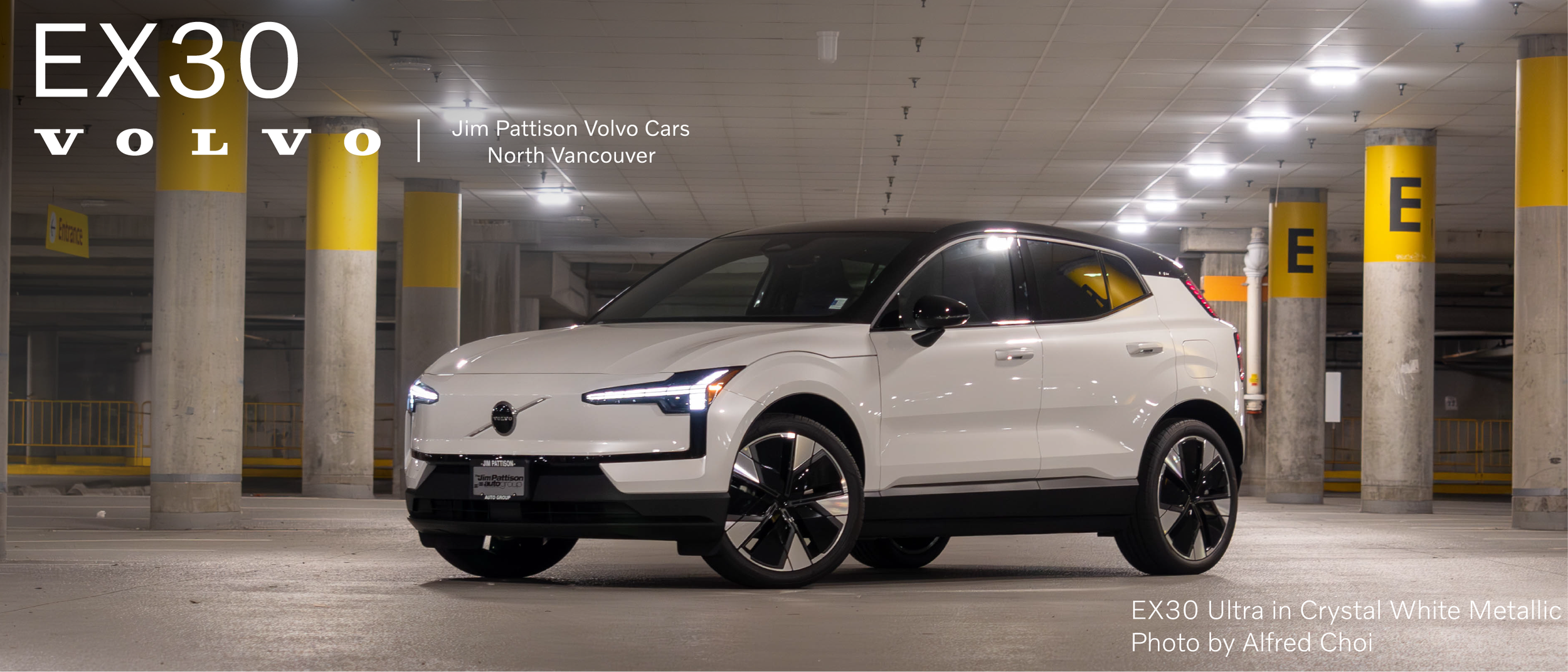 A white Volvo EX30 Ultra parked in an underground parking lot with concrete pillars painted yellow and gray.