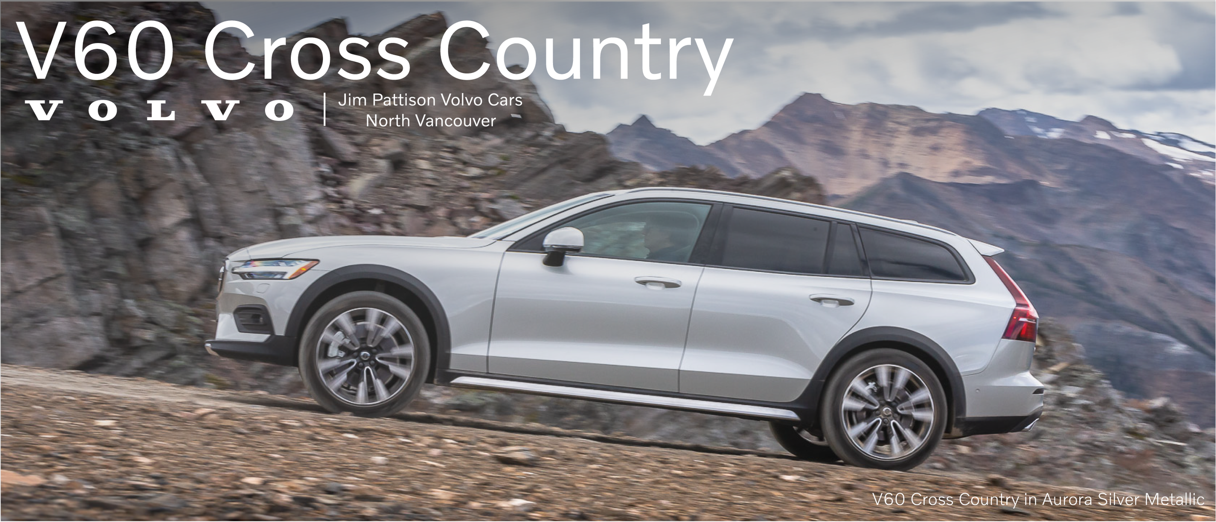A white Volvo V60 Cross Country driving on a rocky mountain trail with cloudy sky and mountain landscape in the background.