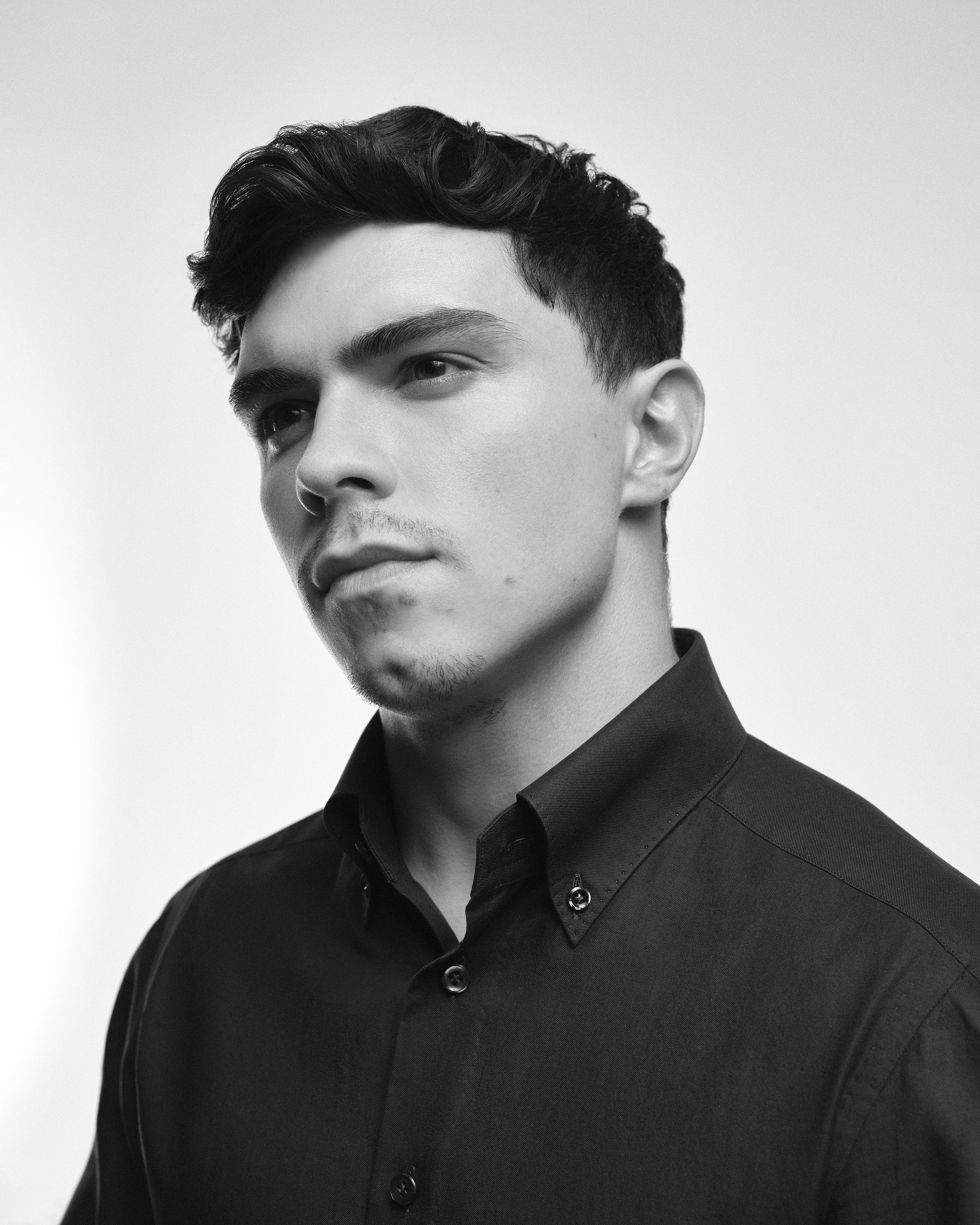 Black and white portrait of a man with short hair wearing a button-up shirt.