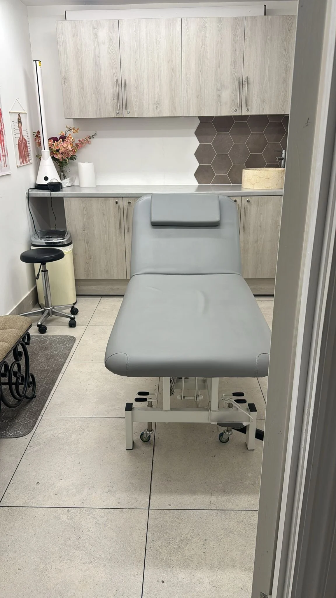 Medical examination room with an examination table, cabinets, and medical posters.