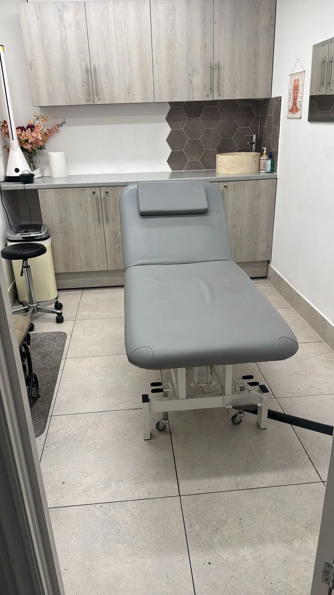 Medical examination room with an examination table, cabinets, and medical supplies.