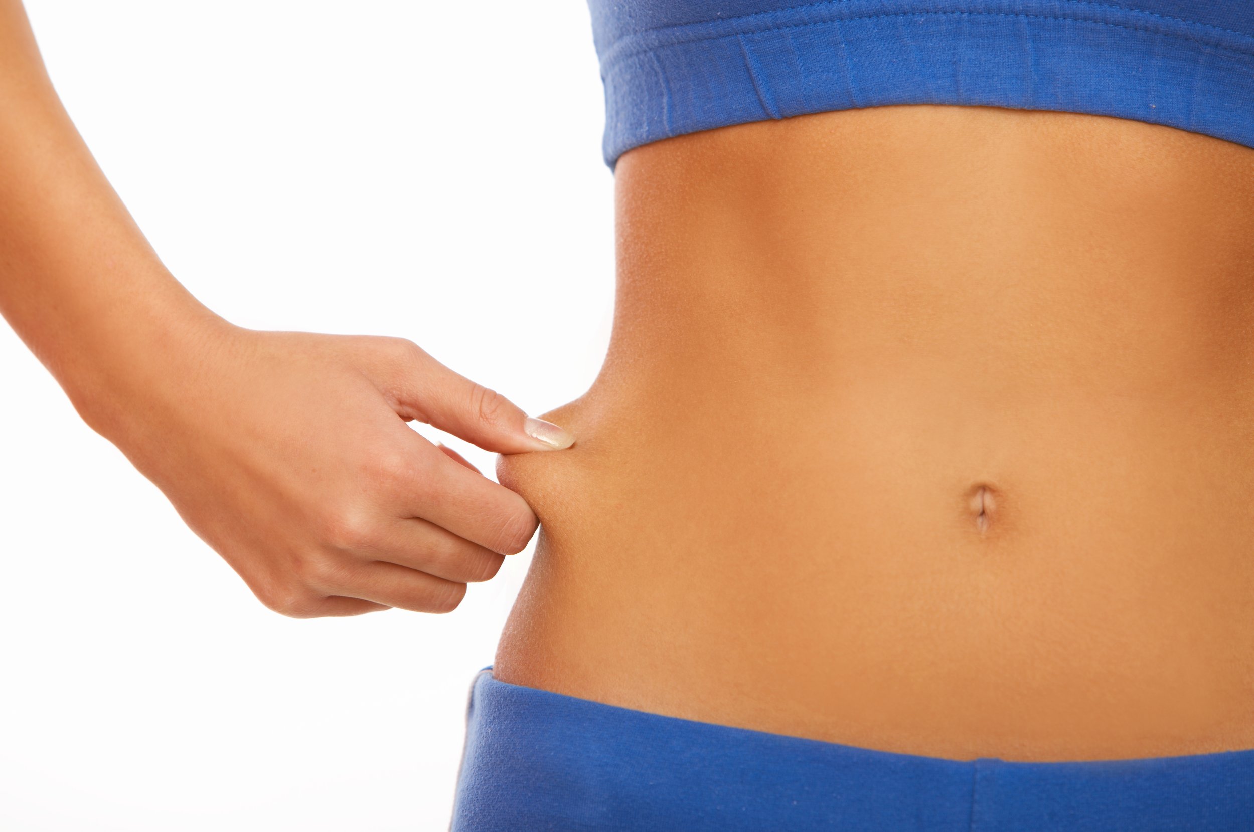 Close-up of a person's hand pinching a small amount of belly fat on their midsection, wearing blue clothing, with smooth, tan skin.