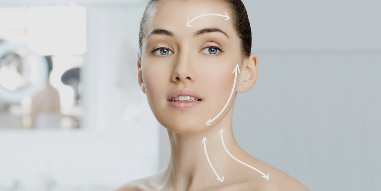 A woman with clear skin and blue eyes looking at the camera, with white arrows drawn on her face and neck indicating areas for facial massage or skincare treatment.