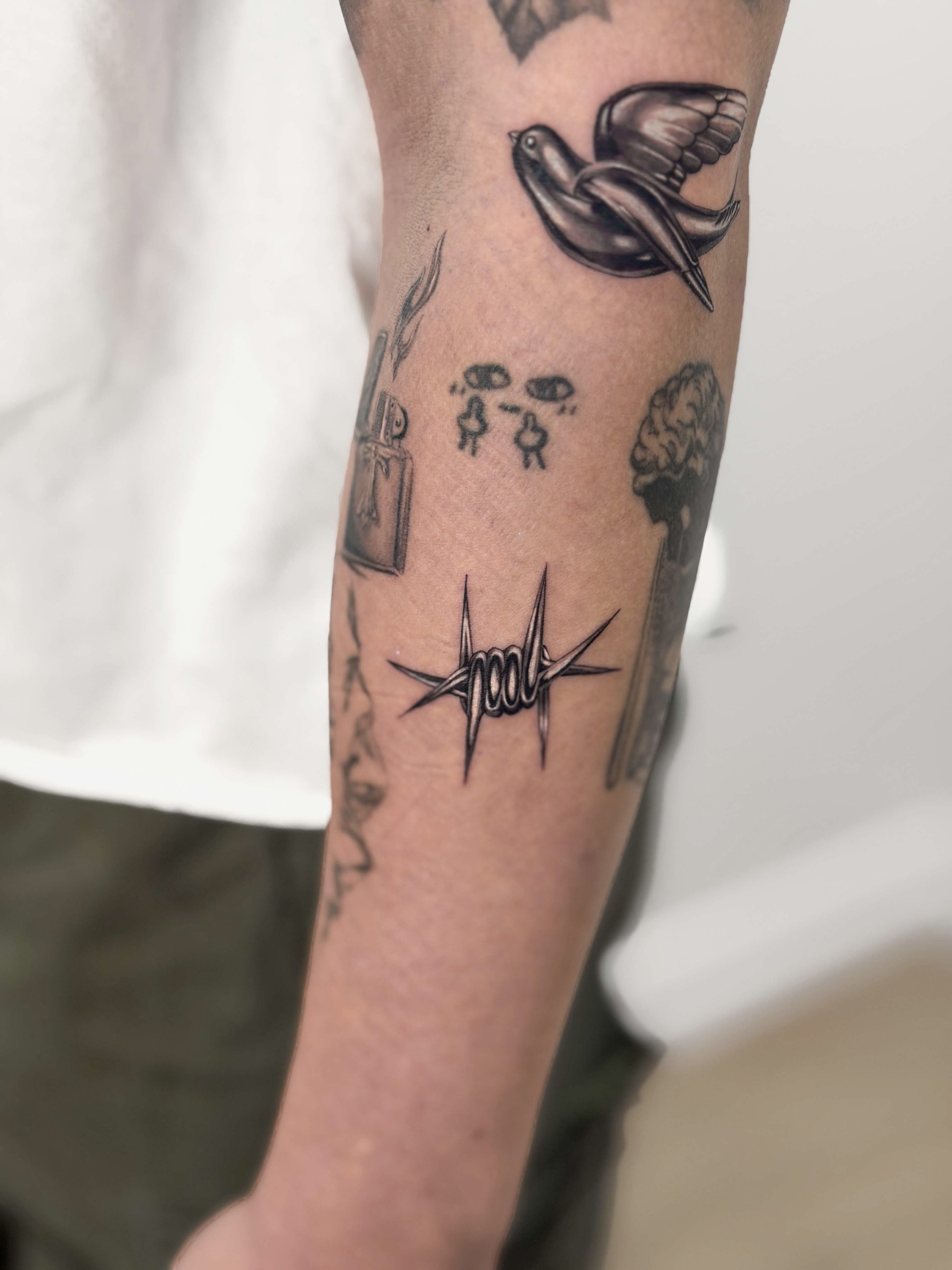 Tattoo chrome effect metal silver barbed wire and swallow bird on a person's forearm.