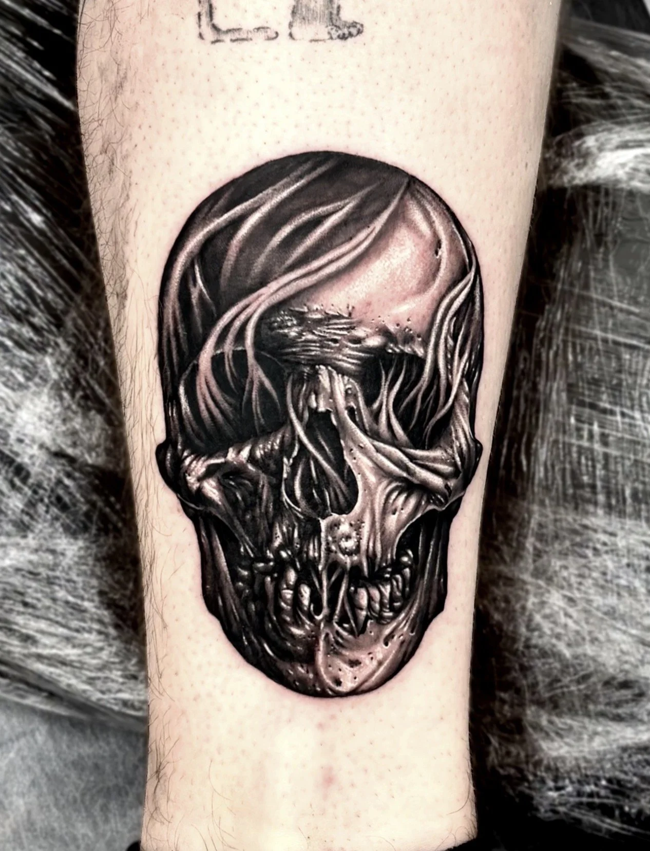 Black and grey realism tattoo of a skull with smoke coming out of its eyes and skeletal features.
