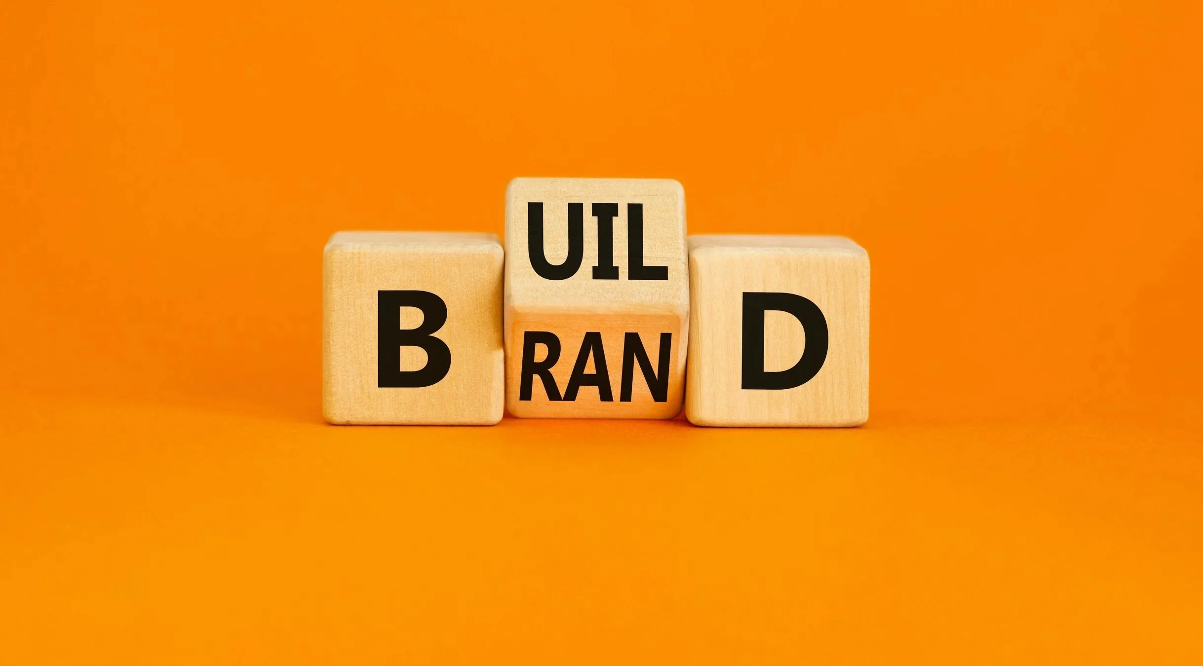 Tre träblock med bokstäver som tillsammans bildar ordet 'Brandbilar', placerade på orange bakgrund.