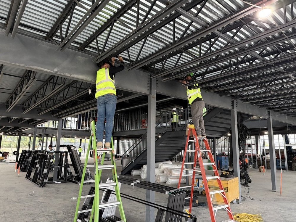 Crew on ladders coordinating low-voltage work in a building under construction