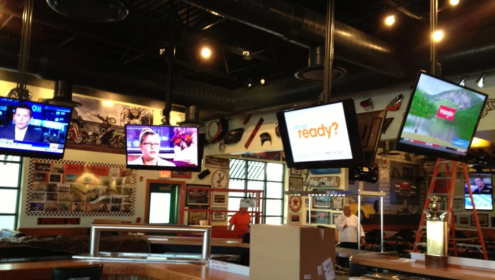 Sports bar with a wall of TVs showing basketball and news, installed by Tri-State AV