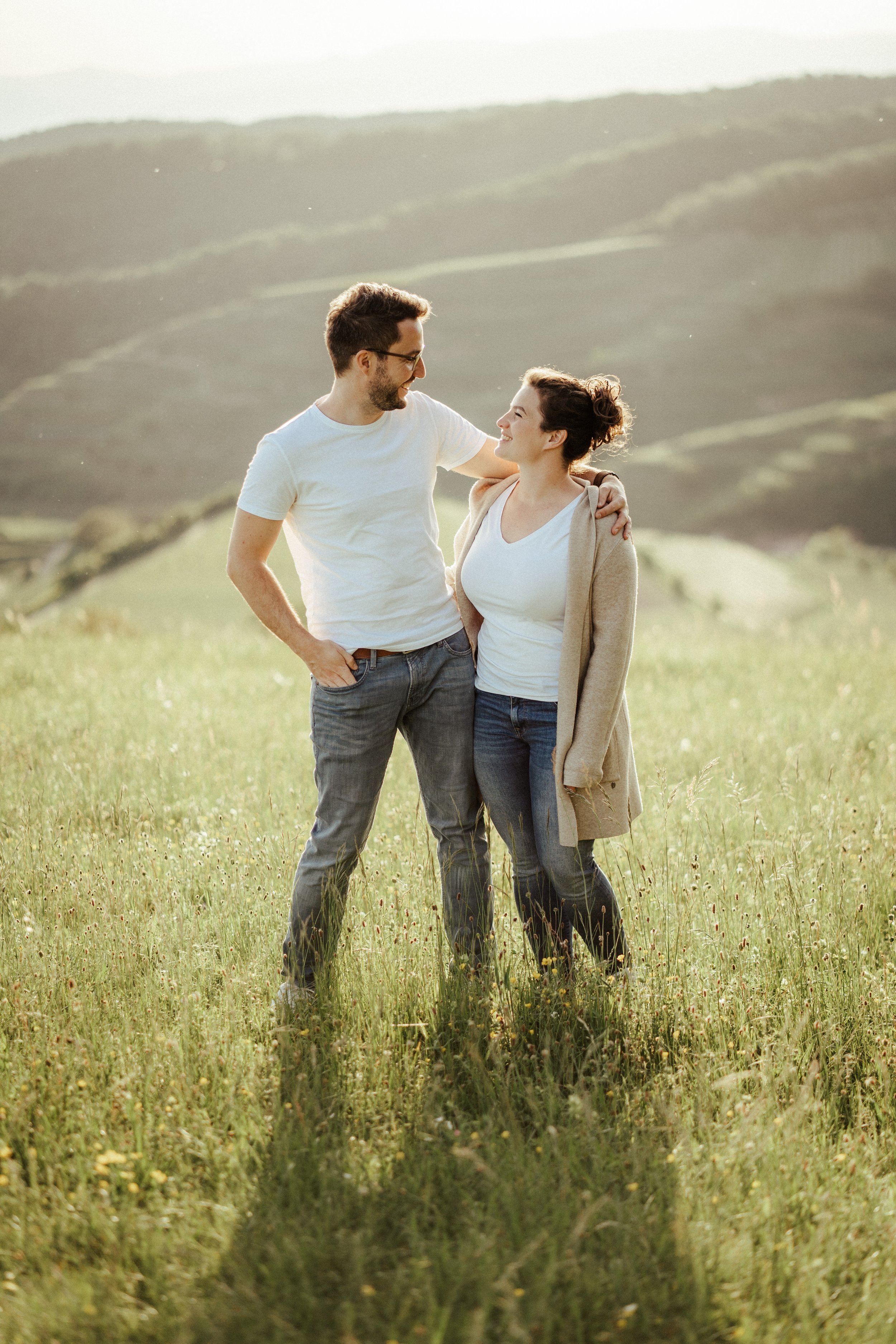 Paar mit weißen T-Shirts schaut sich an vor Weinbergen by UhlArt Fotografie