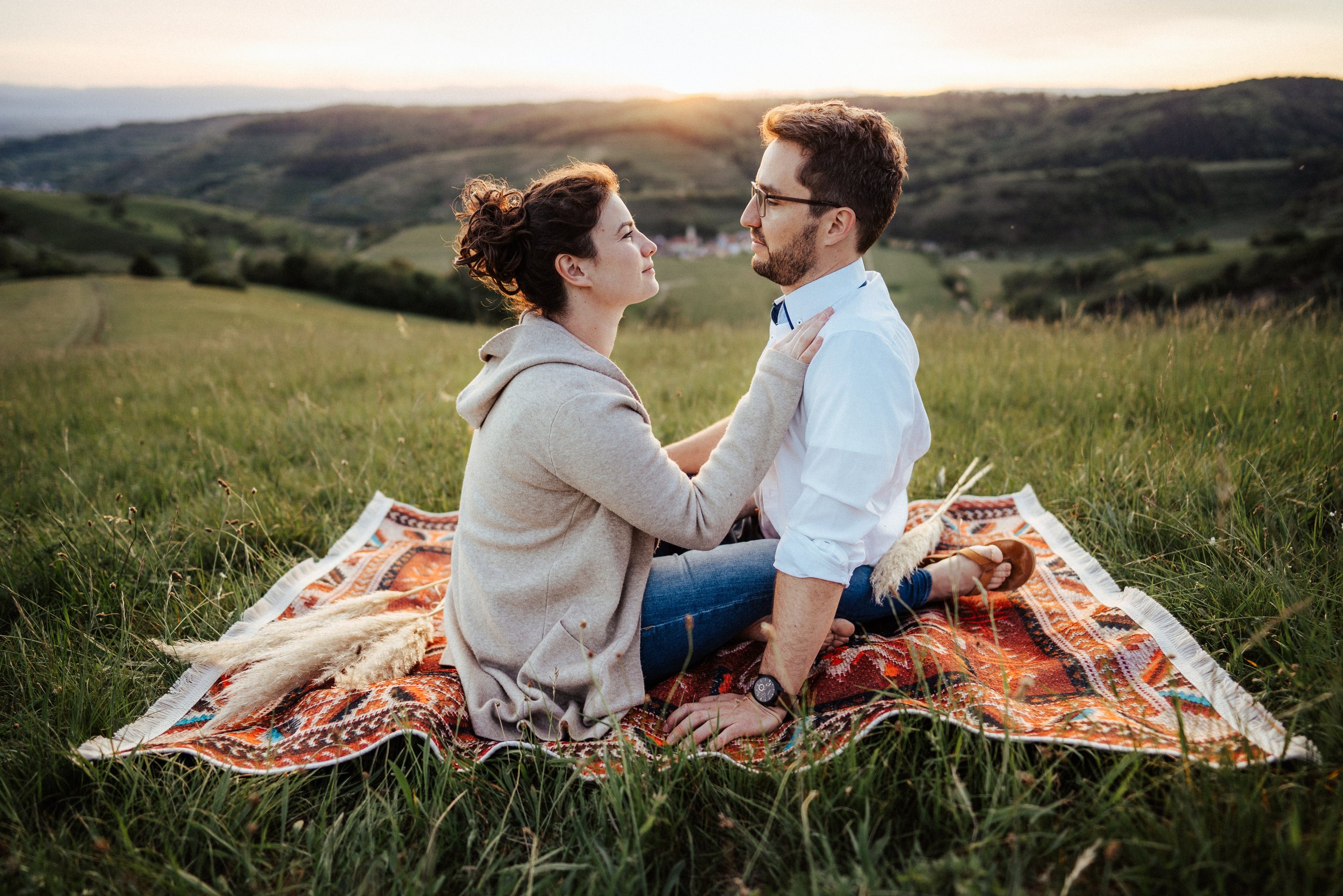 Romantisches Paarshooting: Paar auf einem Teppich in der Wiese bei Sonnenuntergang