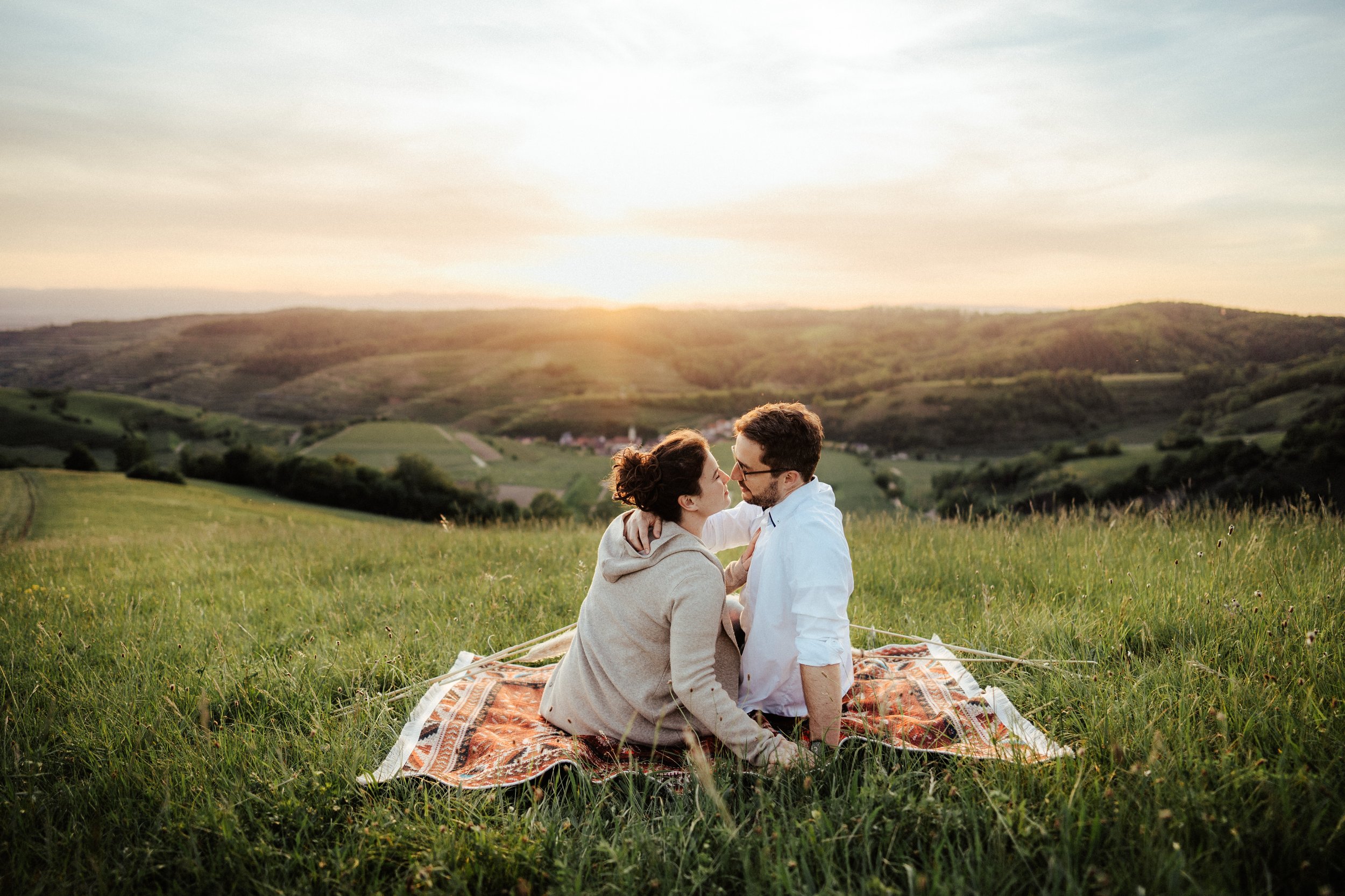 Romantisches Paarshooting: Paar auf einem Teppich in der Wiese bei Sonnenuntergang