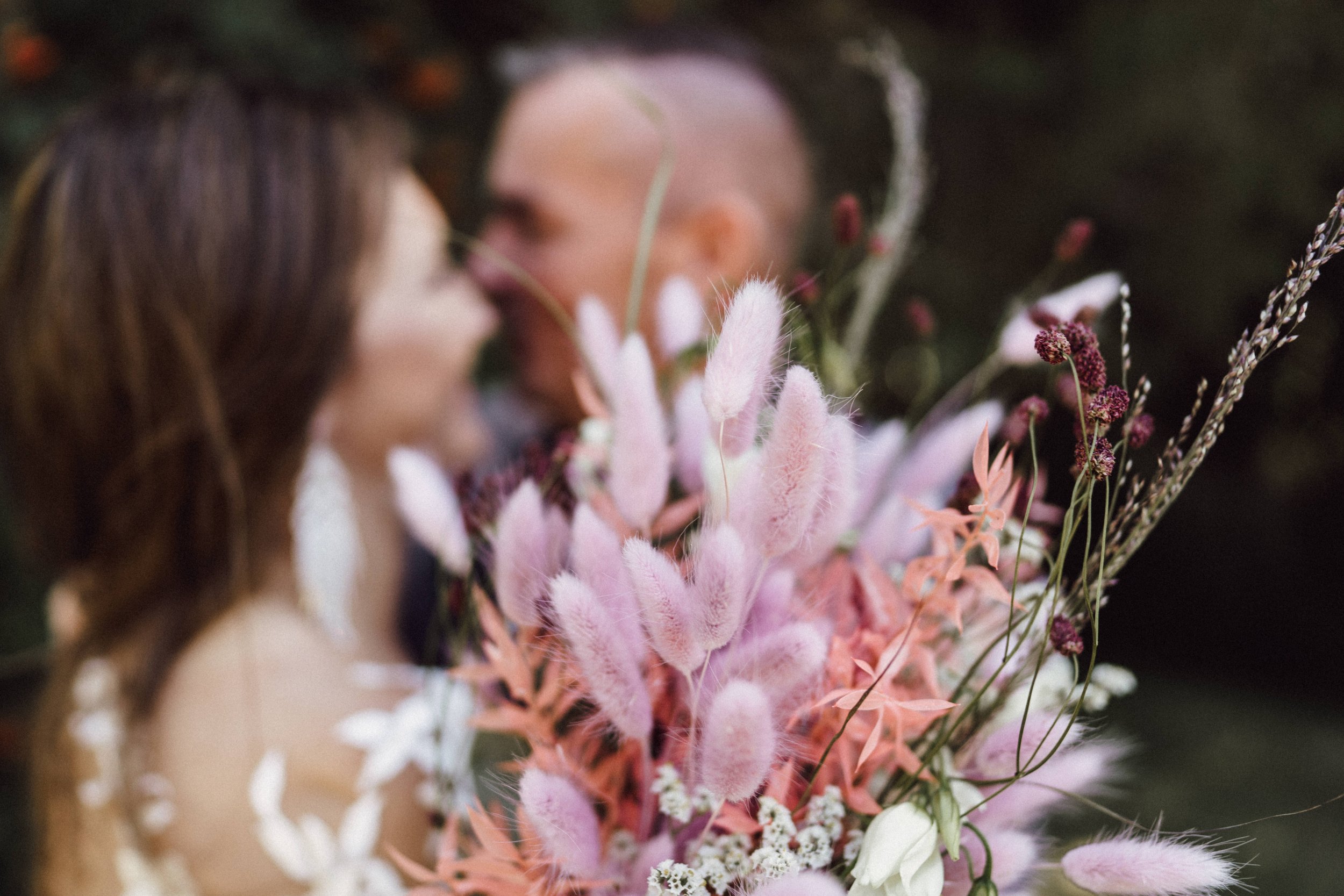 Trockenblumenstrauß mit Brautpaar im Hintergrund by UhlArt Fotografie