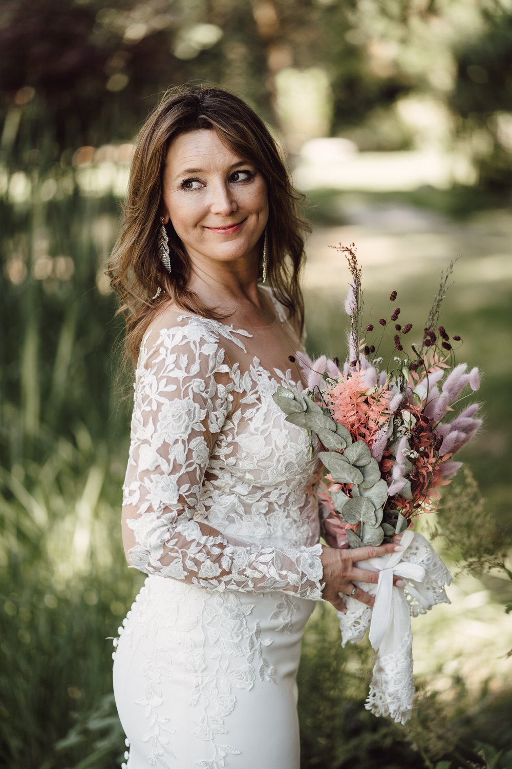 Glückliche Braut im Park mit Trockenblumen
