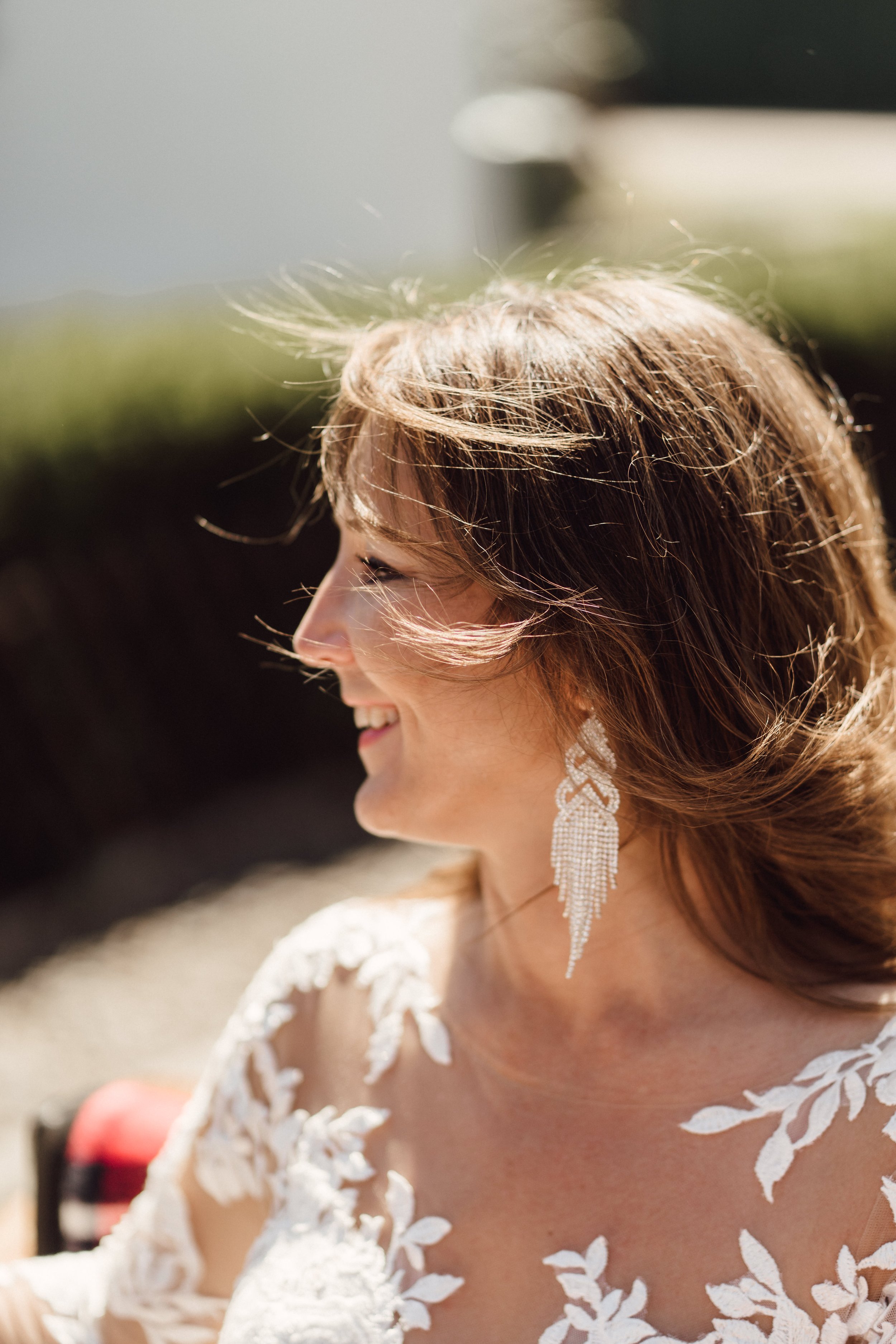 Braut mit wehenden Haaren im Wind mit Spitze und hängenden Ohrringen by UhlArt Fotografie