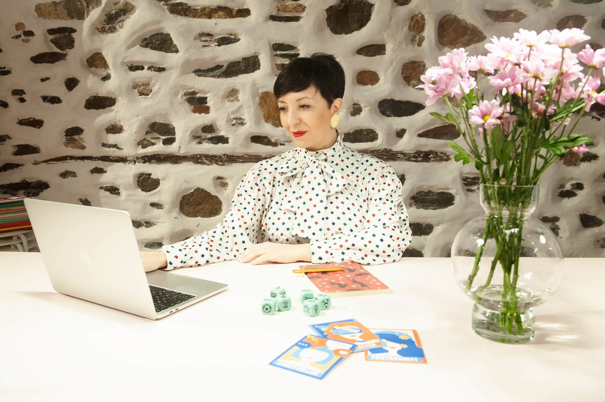 Chiara Aliotta working at her computer. Notebook, cards and other tools scattered on her desk.