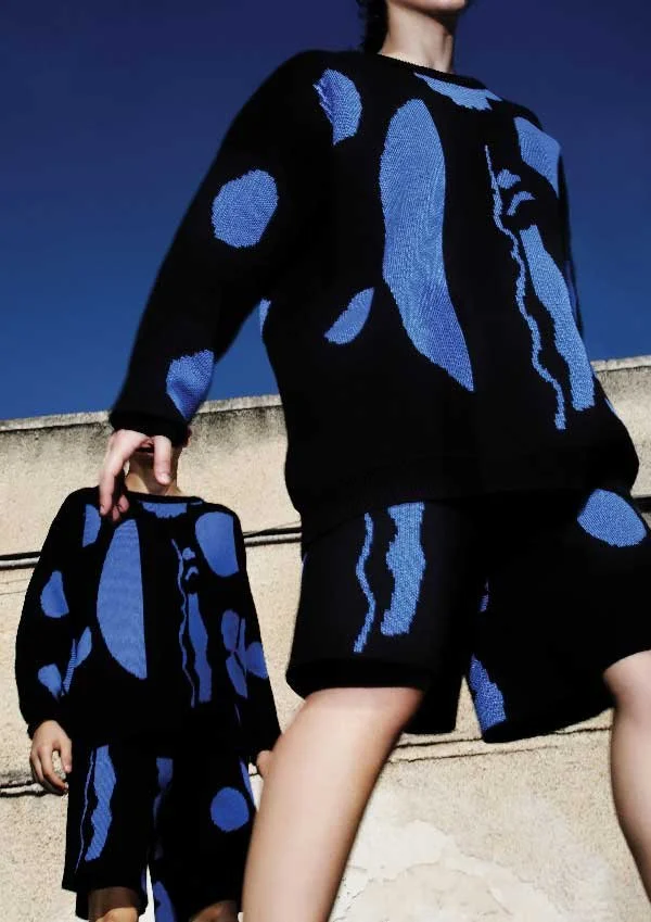 A fashion design showcase featuring matching apparel from M2Patterns for Until Sunday Studio's Creative Exchange. The photograph captures knit sweaters and shorts patterned with abstract blue graphic shapes.