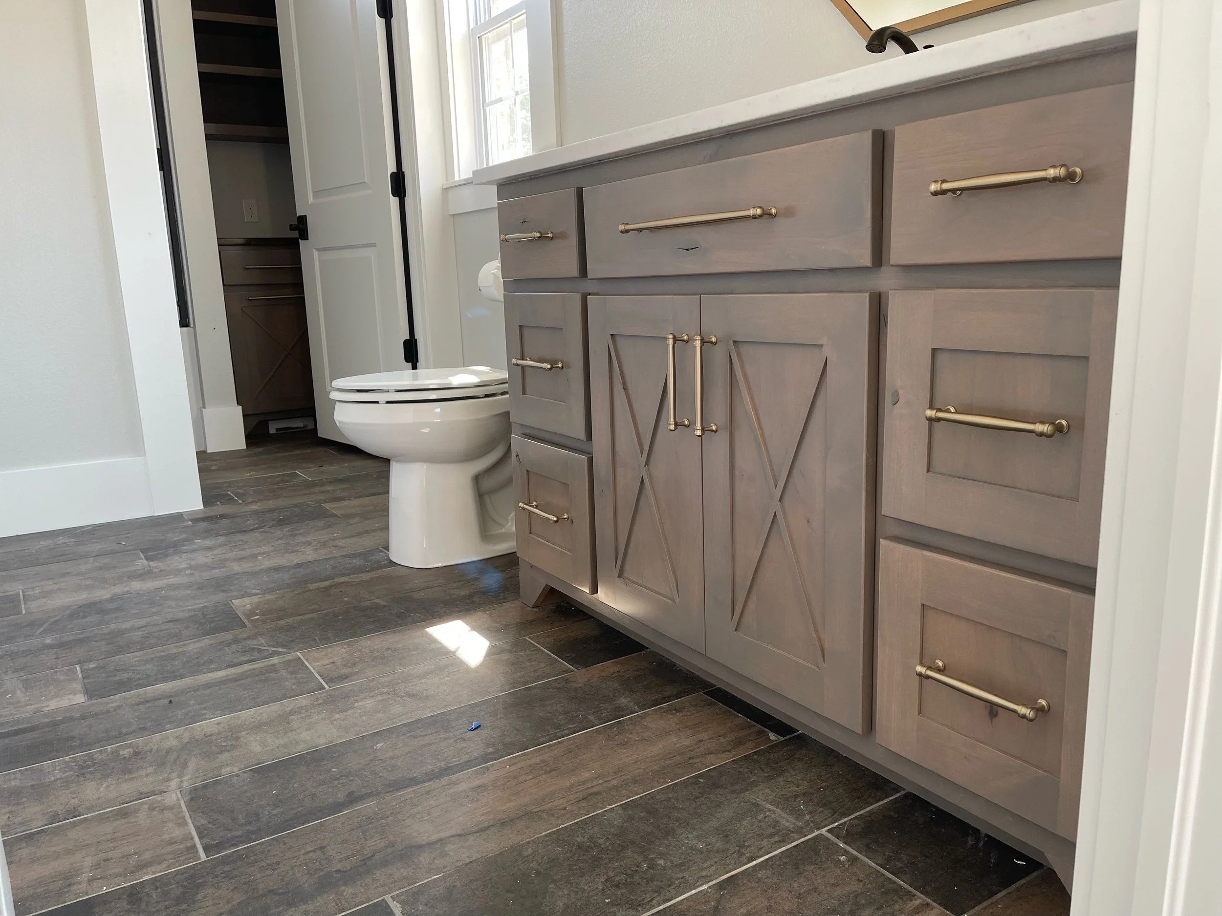 Bathroom with a wooden cabinet, a toilet, and a closet in the background.