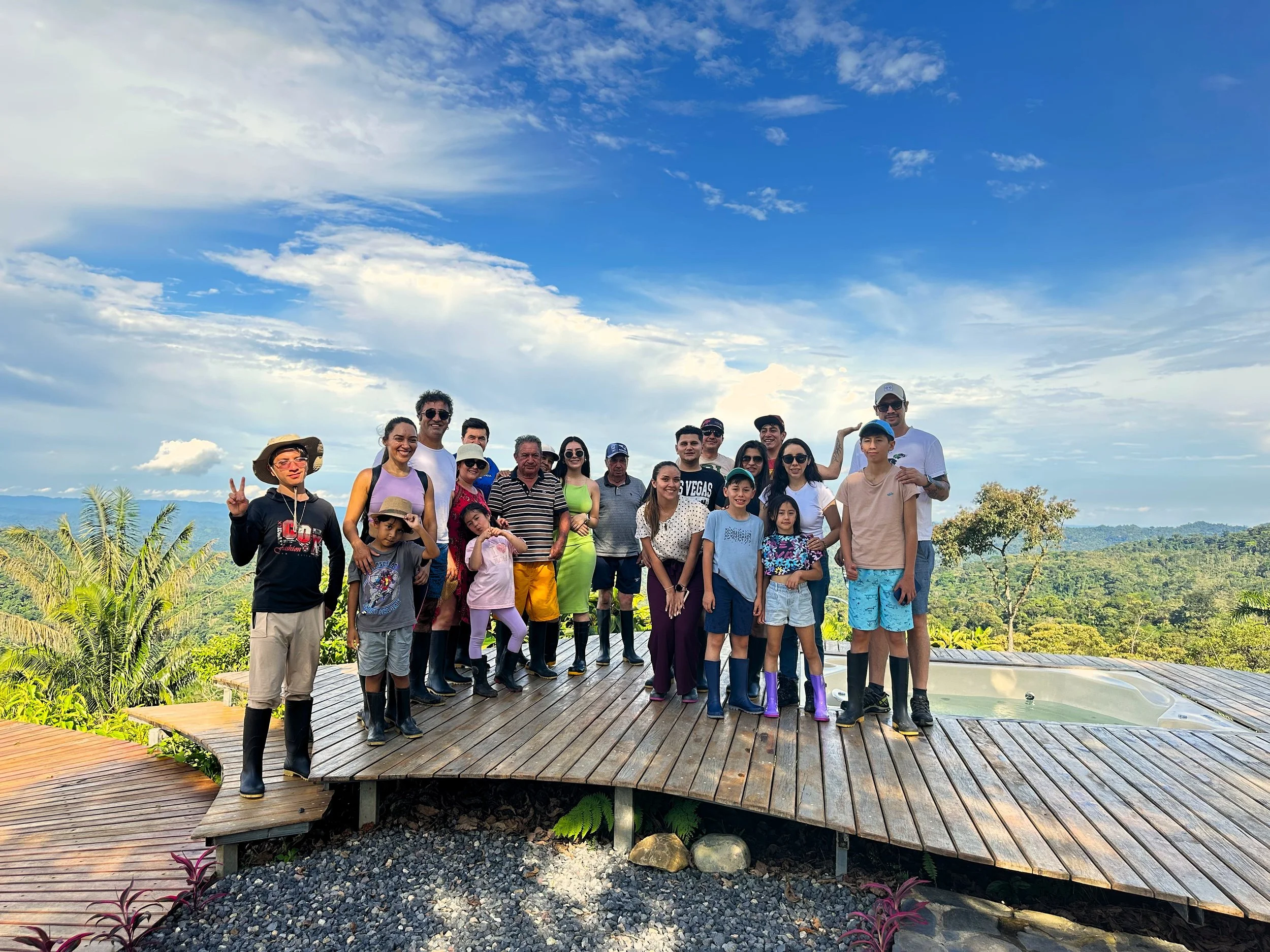 Grupo de personas en el mirador antes de irse a una caminata por la selva con vista panorámica de naturaleza y cielo nublado.
