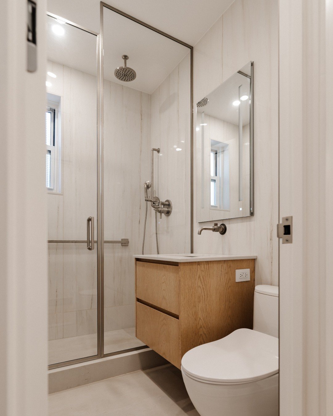 In this bathroom design, we've seamlessly integrated all our favorite design elements and top-notch brands. From the expansive wall tiles to the sleek Robern medicine cabinet, the exquisite Brizio fixtures to the stylish framed shower glass surround,