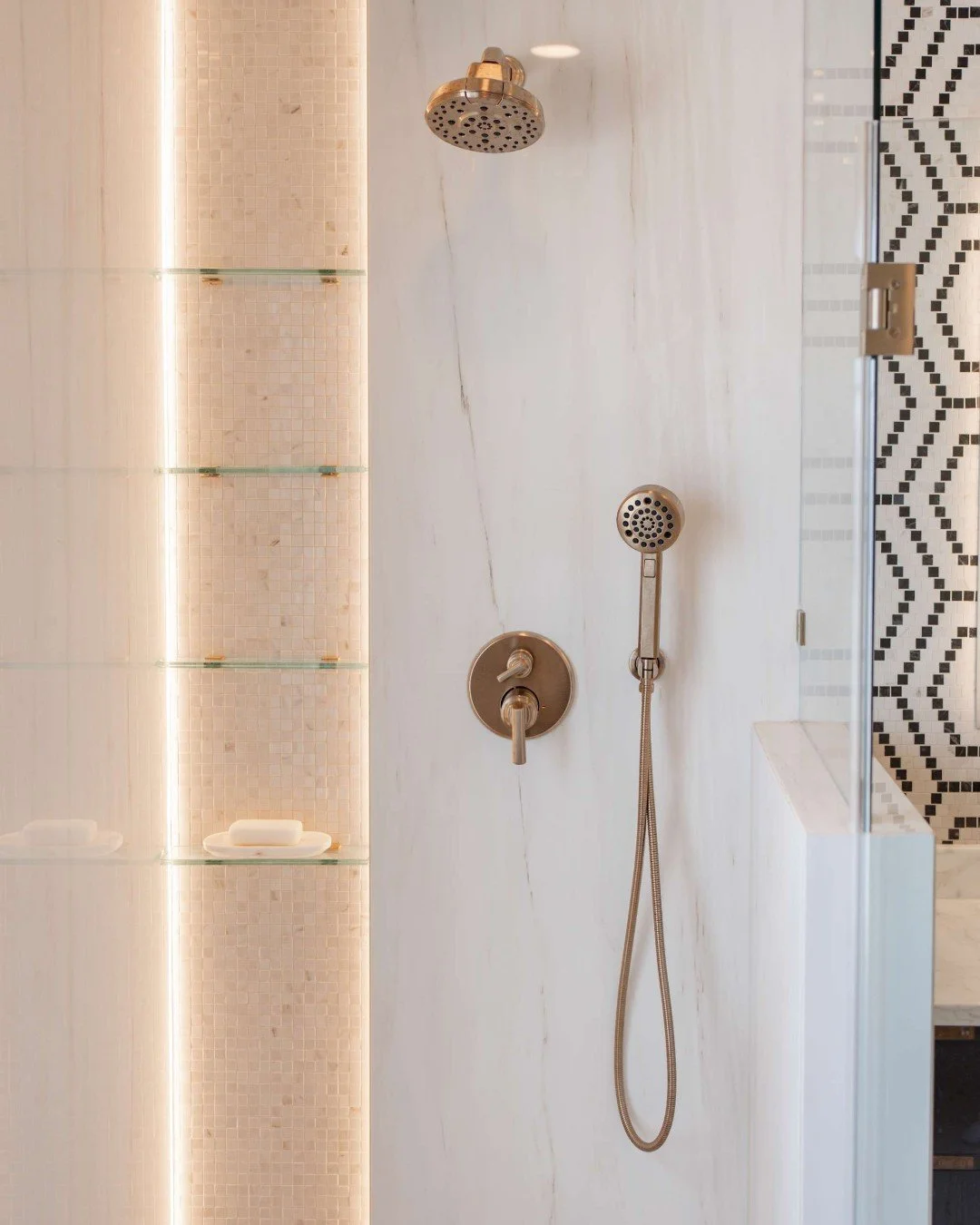 We love how this half of the shower came together &mdash; can you believe this is only half of the shower area? 😳

From the warm brass fixtures and softly lit full-length niche to the seamless slab tile walls and mosaic tile floor, every detail laye