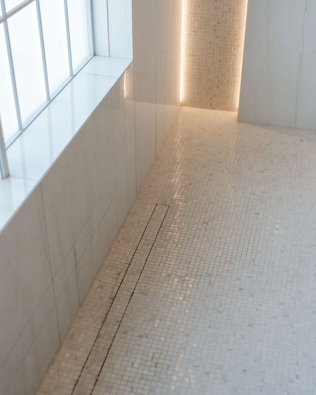 We love the flexibility that small mosaic tiles offer &mdash; they&rsquo;re perfect for unique surfaces like infinity drains and the gentle curves of a shower bench. The smaller tile size also increases the grout lines, adding an extra layer of safet