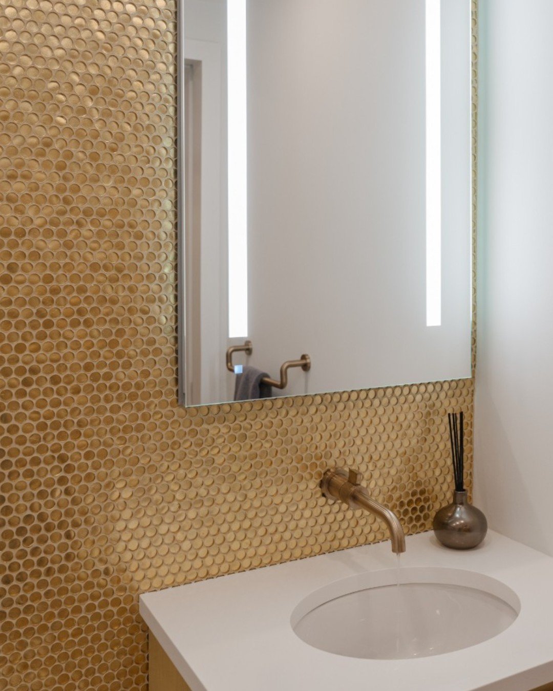 Even small spaces deserve sparkle! This glass penny round mosaic tile in Gold adds cheerful shine and playful texture behind the vanity and toilet. This thoughtful accent transforms a functional space into one that feels inviting, stylish, and full o
