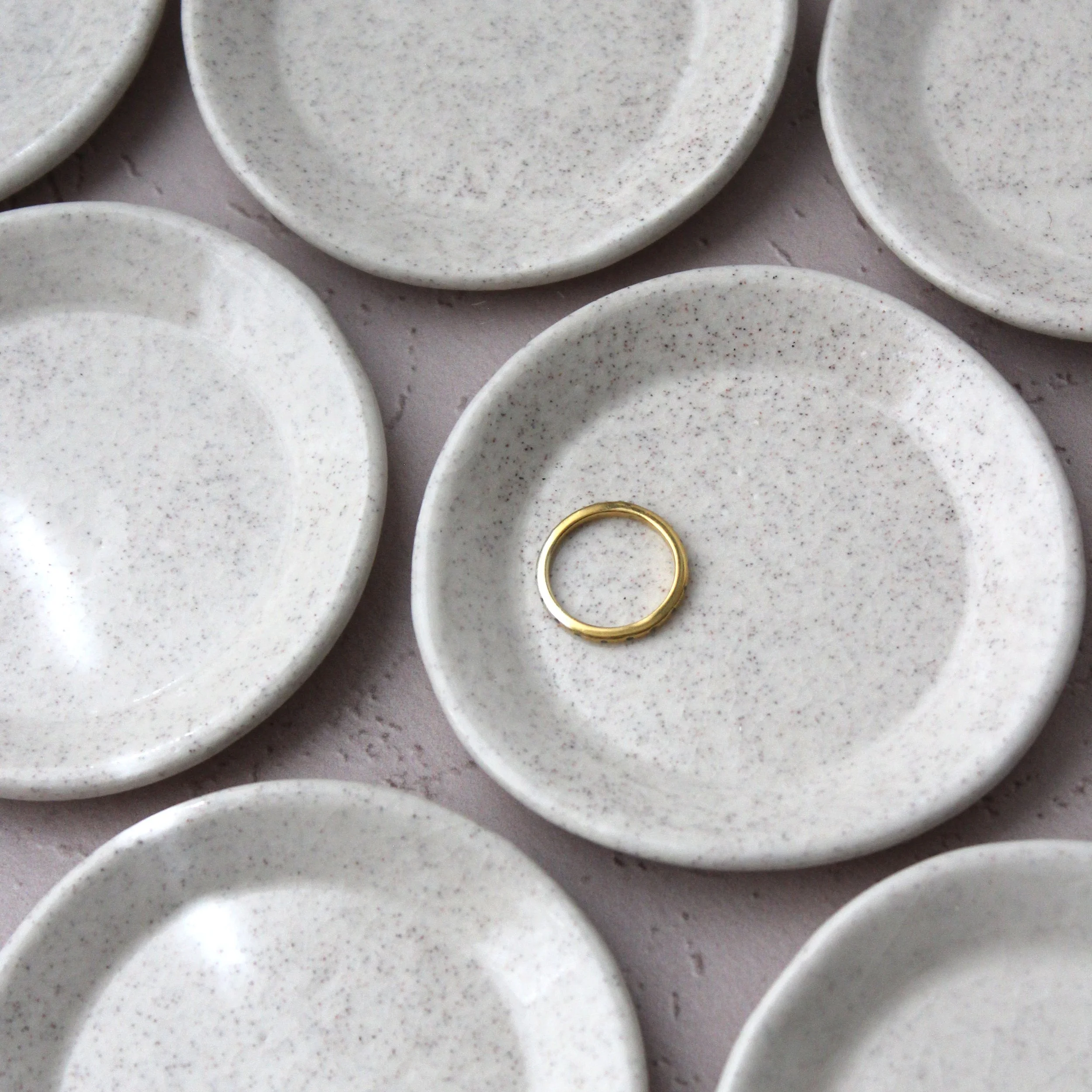 several sand ring dishes with one holding a gold ring
