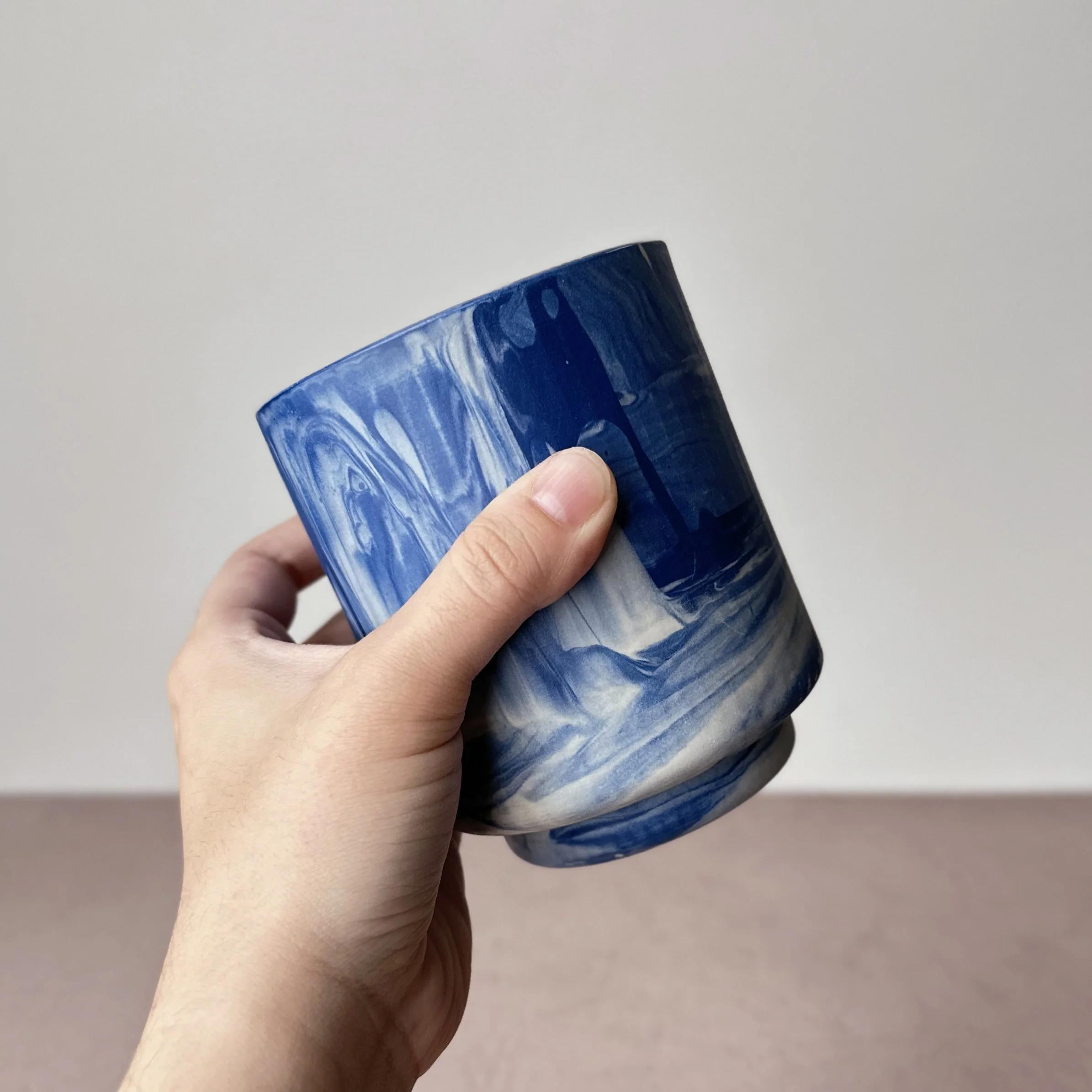 a hand holding a blue marbled tumbler