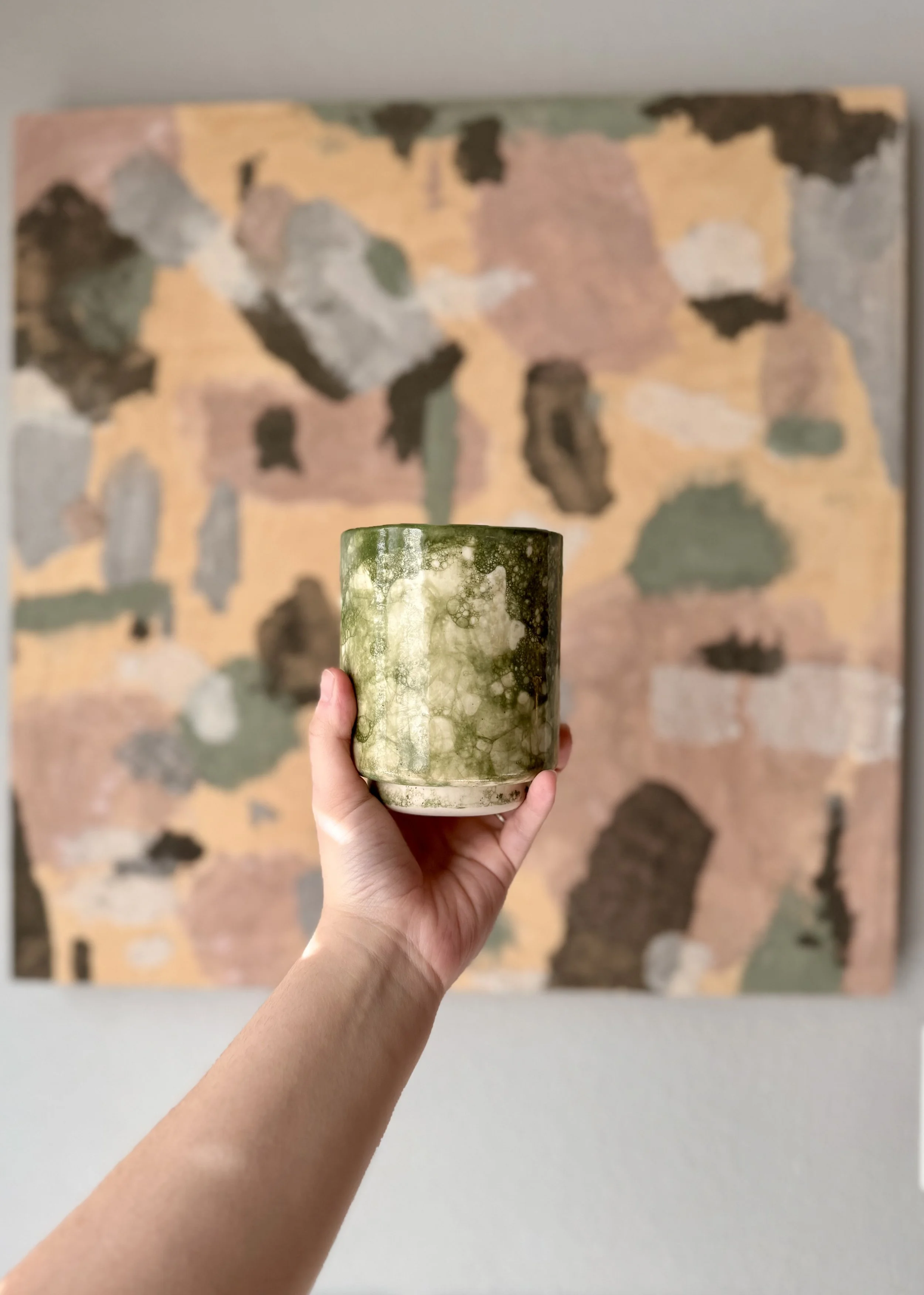hang holding a green glazed tumbler