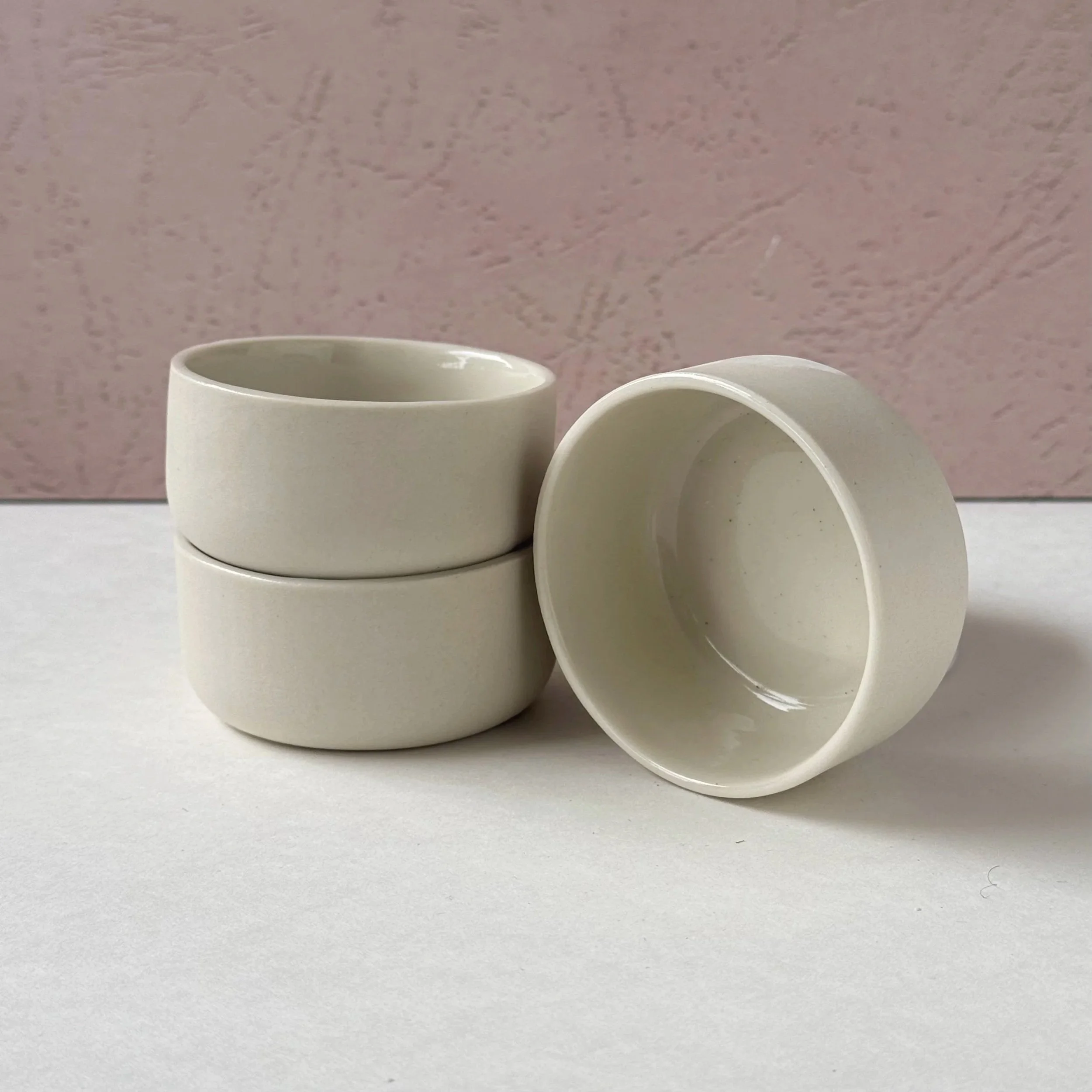 two small cream bowls stacked with one beside it