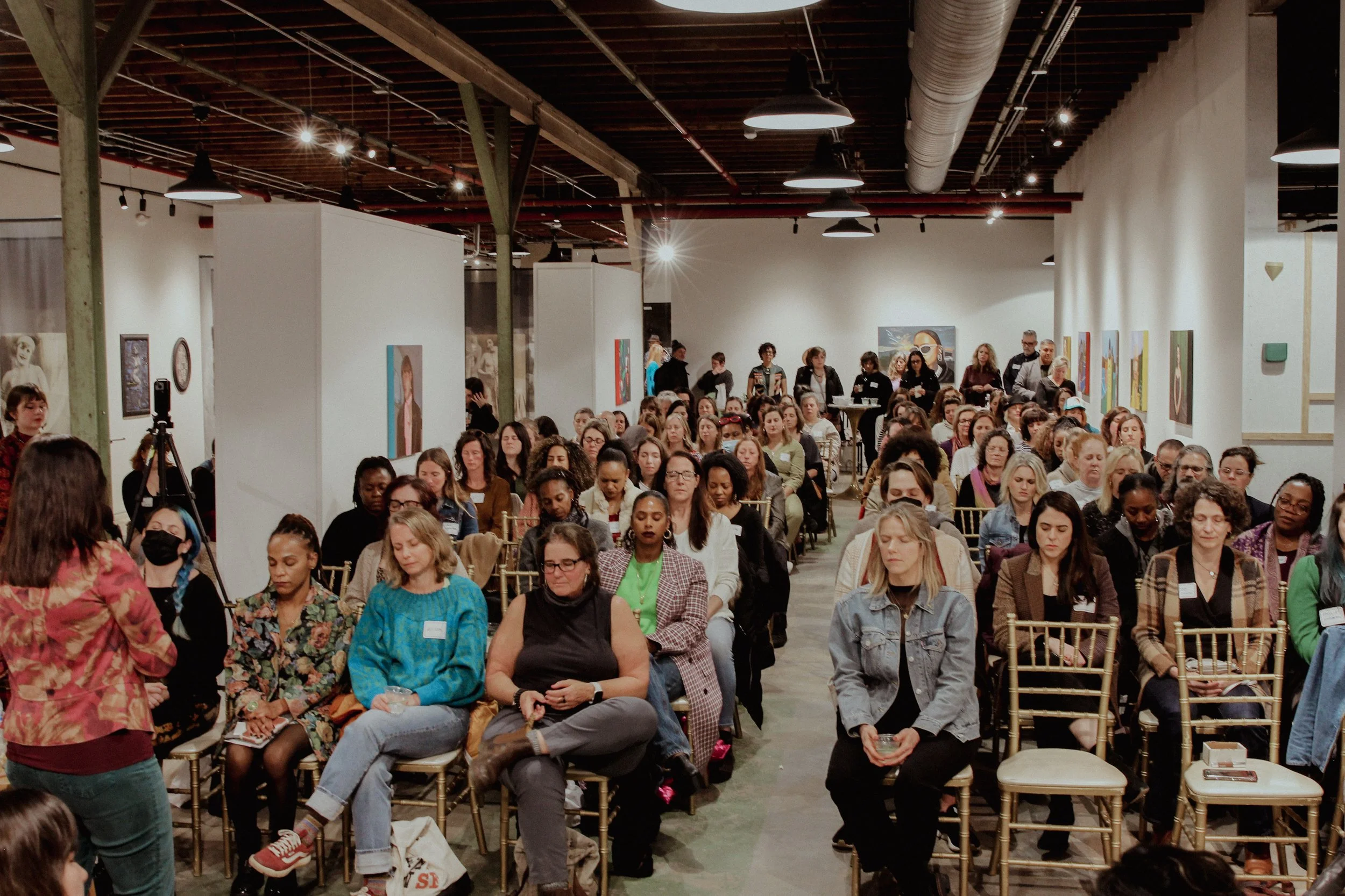 Large audience of women attending a conference or seminar in an art gallery
