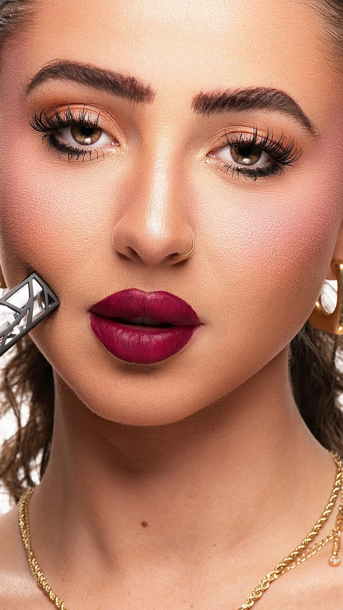 A woman with makeup applying lipstick, with close-up focus on her face showing eye makeup, lipstick, jewelry, and skin details. Cleveland Photographer. Cleveland Portrait. The Lib Bar
