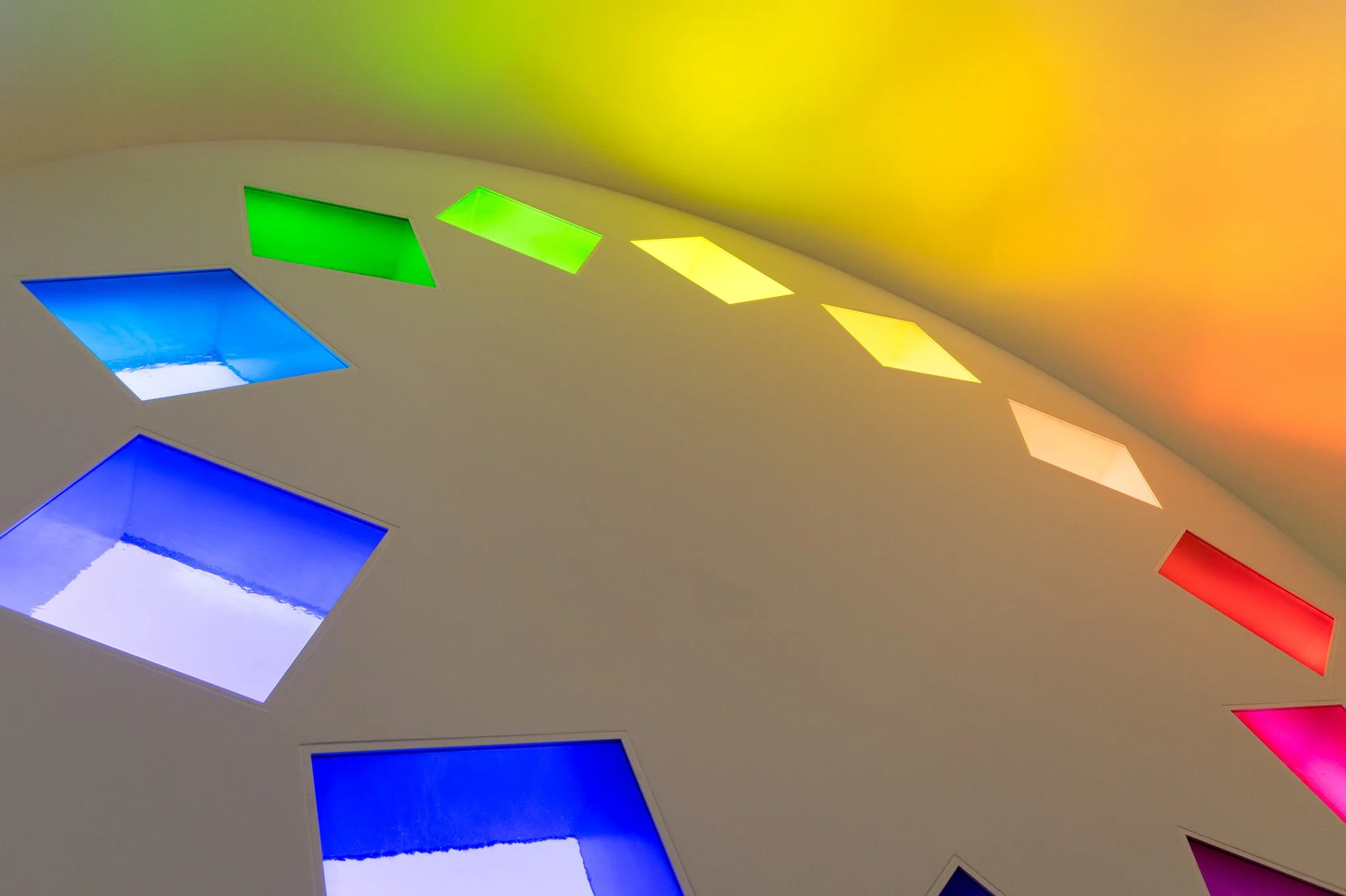The color spectrum depicted in squares of colored glass in a radial configuration in a chapel by artist, Ellsworth Kelly. A modern take on the tradition of decorative stained glass rosette windows in medieval European cathedrals.