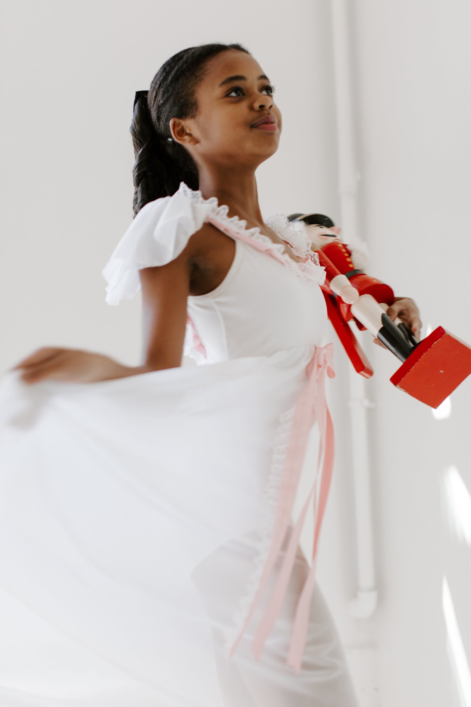 A young dancer as Clara twirling in a white nightgown and holding a nutcracker