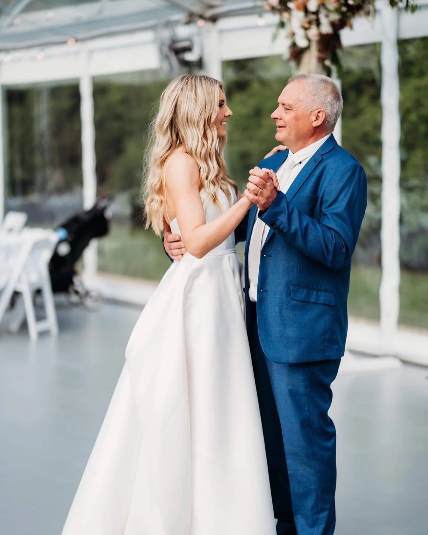 A bride and an older man, possibly her father, dancing together at a wedding reception.