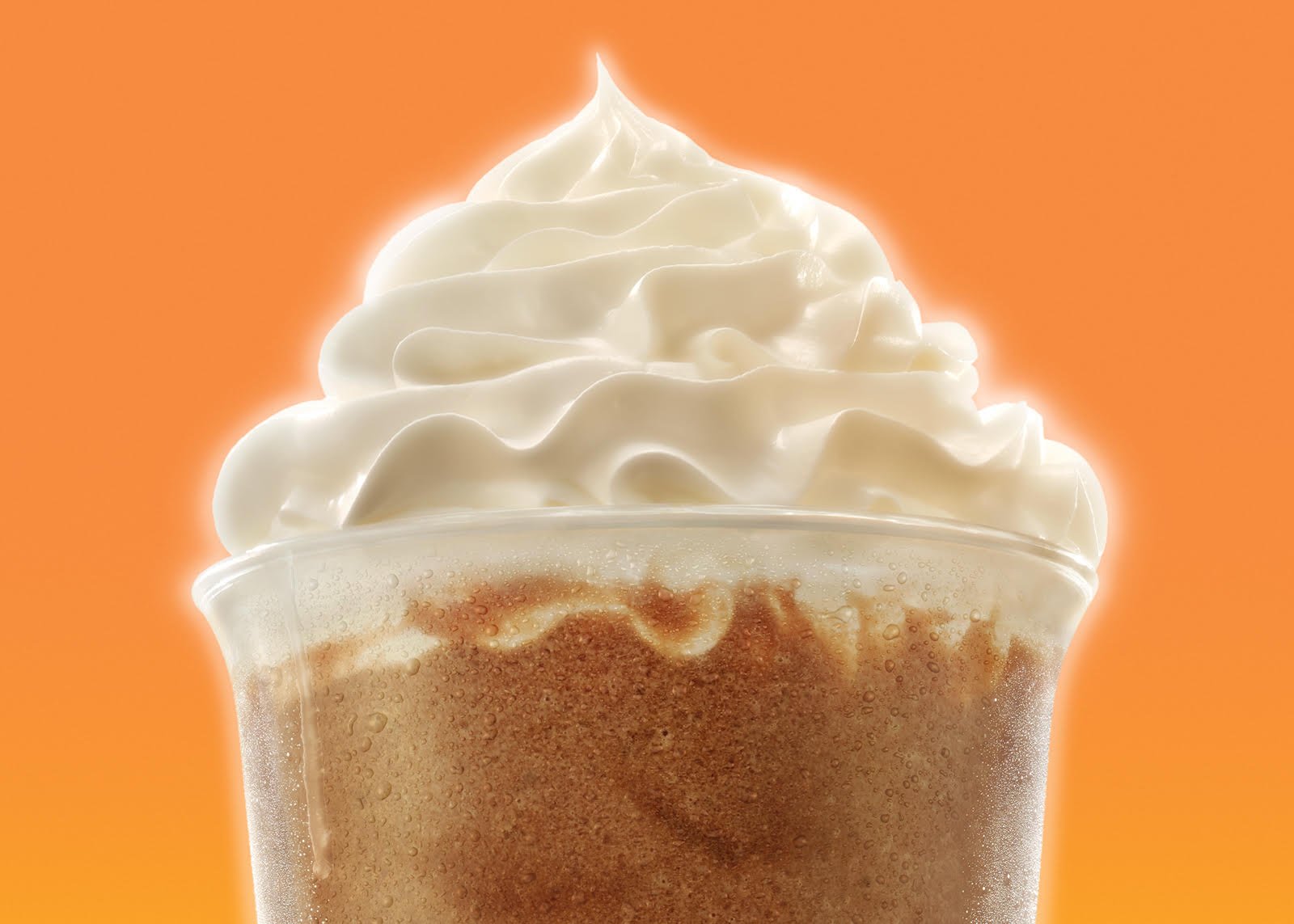 McDonald's McCafe new drink range OOH campaign with Widen + Kennedy. Close-up of a cold glass of coffee topped with whipped cream against an orange background.