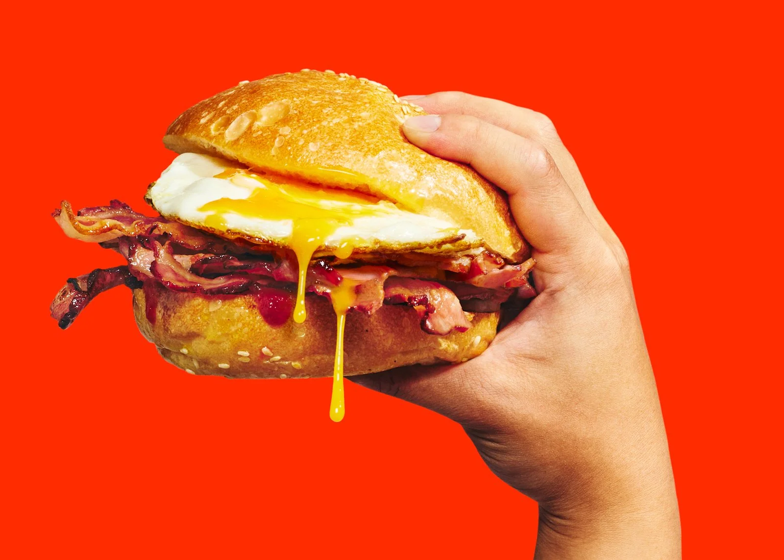 Doordash advertising campaign ''smash it''.  A hand holding a bacon, egg roll on a bright red background.