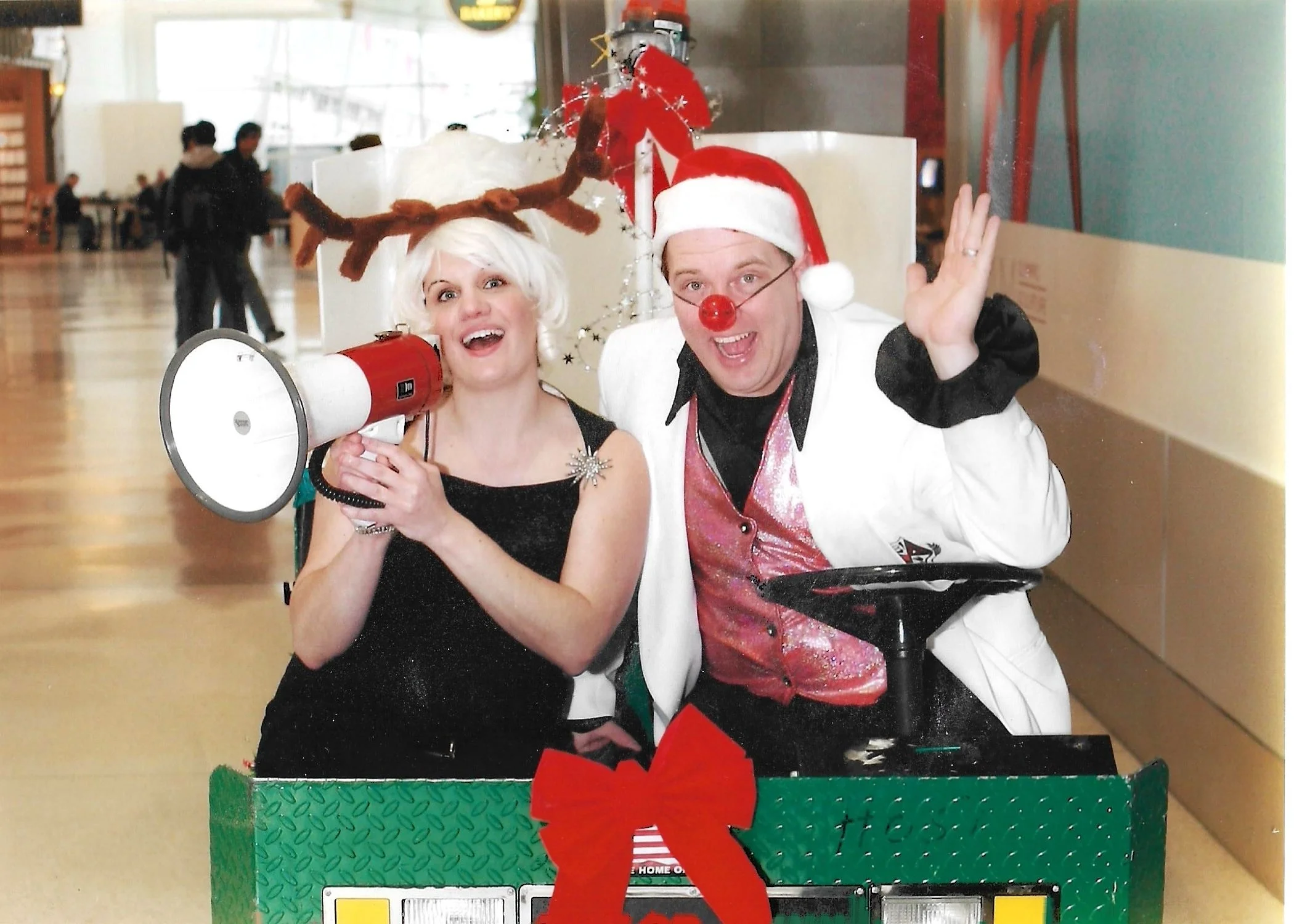 A man and woman in Christmas attire in a golf cart