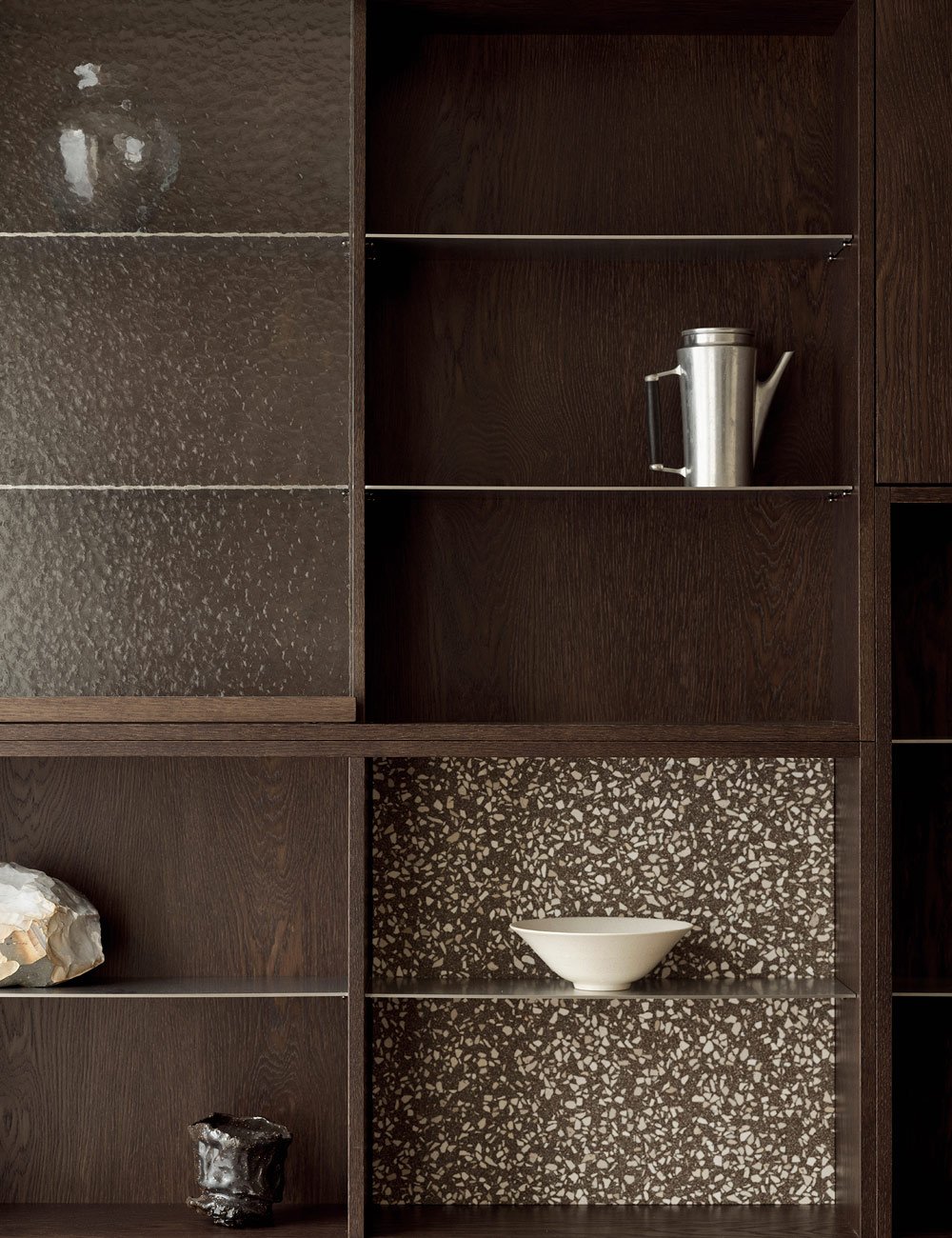 Udstillingsskab i mørk eg med hamret glas, terrazzo og hylder i rustfrit stål.