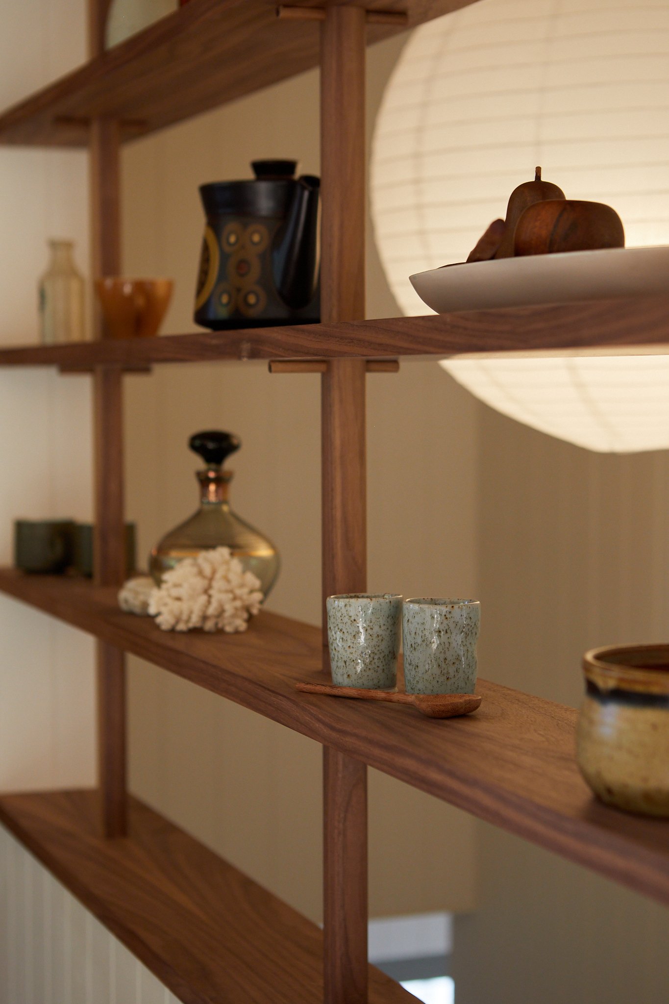 Wooden shelf displaying various decorative items, with a large round paper lantern light in the background.